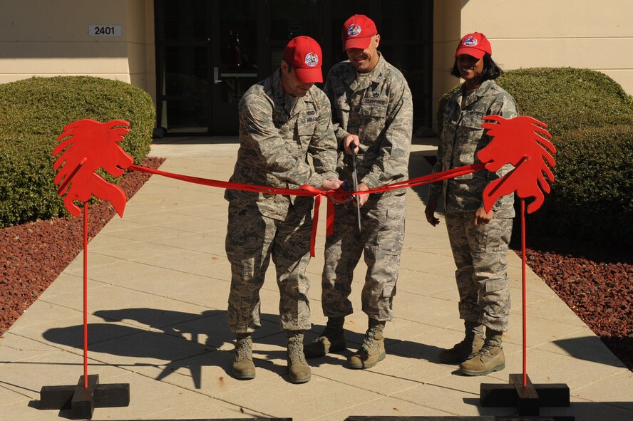 Second lt. Terrance Mathiew, Col. Timothy Lamb and Airman 1st Class Aurora McIver cut a ceremonial ribbon during grand opening of the new 567th REDHORSE facility on Seymour Johnson Air Force Base, N.C., March 6, 2010. The RED HORSE acronym stands for Rapid Engineer Deployable, Heavy Operational Repair Squadron, Engineer. The squadron is a rare self-sufficient mobile unit that provides constructional support across the globe. (U.S. Air Force photo/Senior Airman Ciara Wymbs)