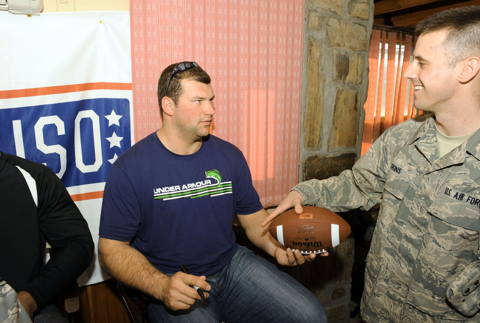 Joe Thomas of the Cleveland Browns signs a football for Senior Airman Joshua Adkins during an autograph session March 5, 2010, at the Pat Tillman USO lounge at Bagram Airfield, Afghanistan. Airman Adkins is an American Forces Network broadcaster. (U.S. Air Force photo/Staff Sgt. Richard Williams)