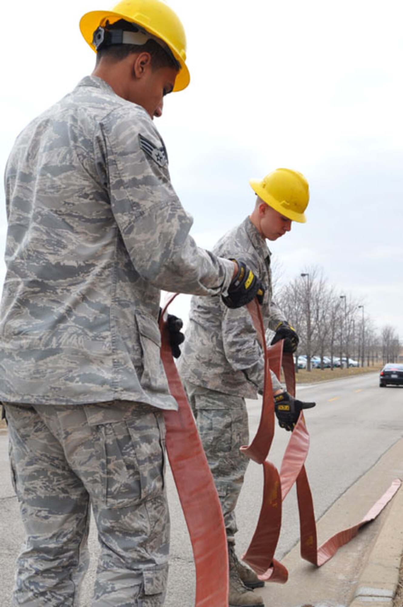 SCOTT AIR FORCE BASE, Ill -- Senior Airman Earl Balthazar and Airman 1st Class Brad Jacobs straighten a hose used to sump water that fills the manholes during the rainy season March 2.  The 375th Communication Squadron's cable maintenance element or Cable Dawgs are a vital to providing communication capability for Scott Air Force Base. The Cable Dawgs are charged with sustaining the voice systems in support of US Transportation Command, Air Mobility Command headquarters, 18th Air Force, 618th Tanker Airlift Control Center, three flying wings and more than 50 associate units. (U.S. Air Force photo by Senior Airman Teresa M. Jennings)