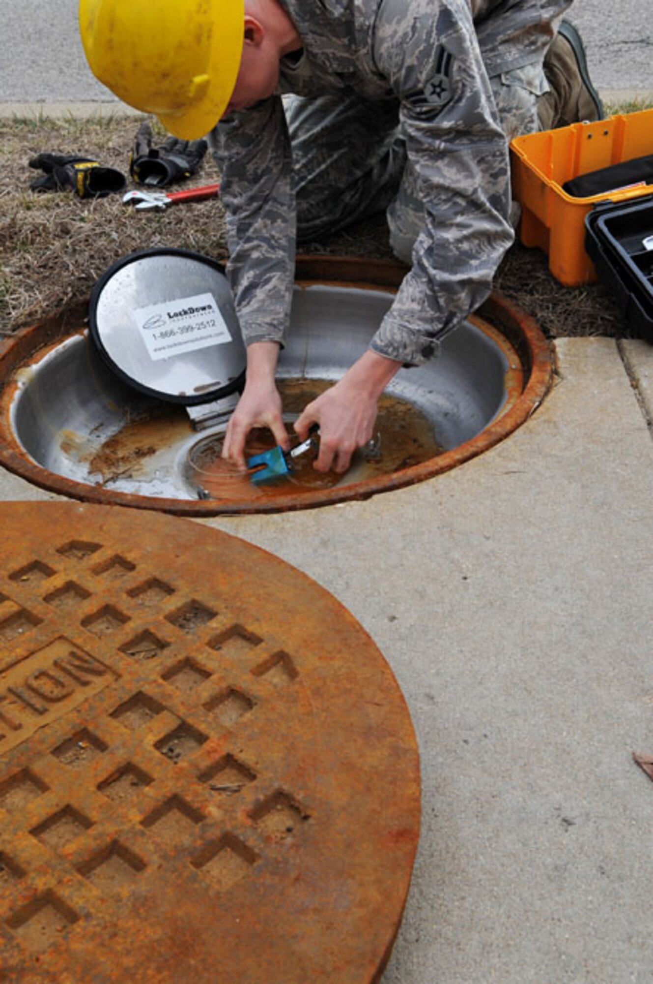 SCOTT AIR FORCE BASE, Ill --Airman 1st Class Brad Jacobs unlocks the second cover for a communications manhole. Airman Jacobs will need to get into the manhole to check the cables that run underground from the new CDC building March 2, 2010. The 375th Communication Squadron's cable maintenance element or Cable Dawgs are a vital to providing communication capability for Scott Air Force Base. The Cable Dawgs are charged with sustaining the voice systems in support of US Transportation Command, Air Mobility Command headquarters, 18th Air Force, 618th Tanker Airlift Control Center, three flying wings and more than 50 associate units. (U.S. Air Force photo by Senior Airman Teresa M. Jennings)