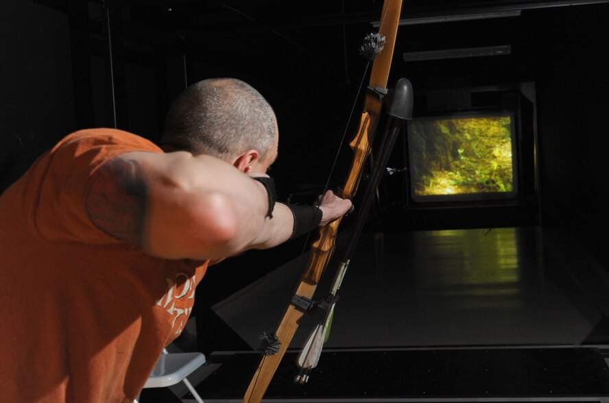MINOT AIR FORCE BASE, N.D. – Tech. Sgt. Thomas Dow, 5th Bomb Wing public affairs web editor, fires an arrow in the archery simulator range at Minot Air Force Base March 8. The outdoor recreation center received the virtual range last September and is currently holding a league competition which began March 1.  The nine-week league will conclude April 24, with a trophy going to the top two-person team. (U.S. Air Force photo by Tech. Sgt. Lee A. Osberry Jr.)