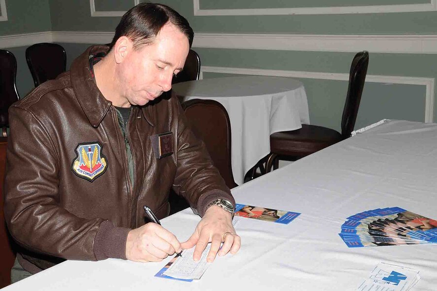 OFFUTT AIR FORCE BASE, Neb. -- Brig. Gen. John N.T. Shanahan, 55th Wing commander, makes a monetary contribution to kick off the Air Force Assistance Fund Drive at the Patriot Club here March 4. U.S. Air Force photo by Kendra Williams