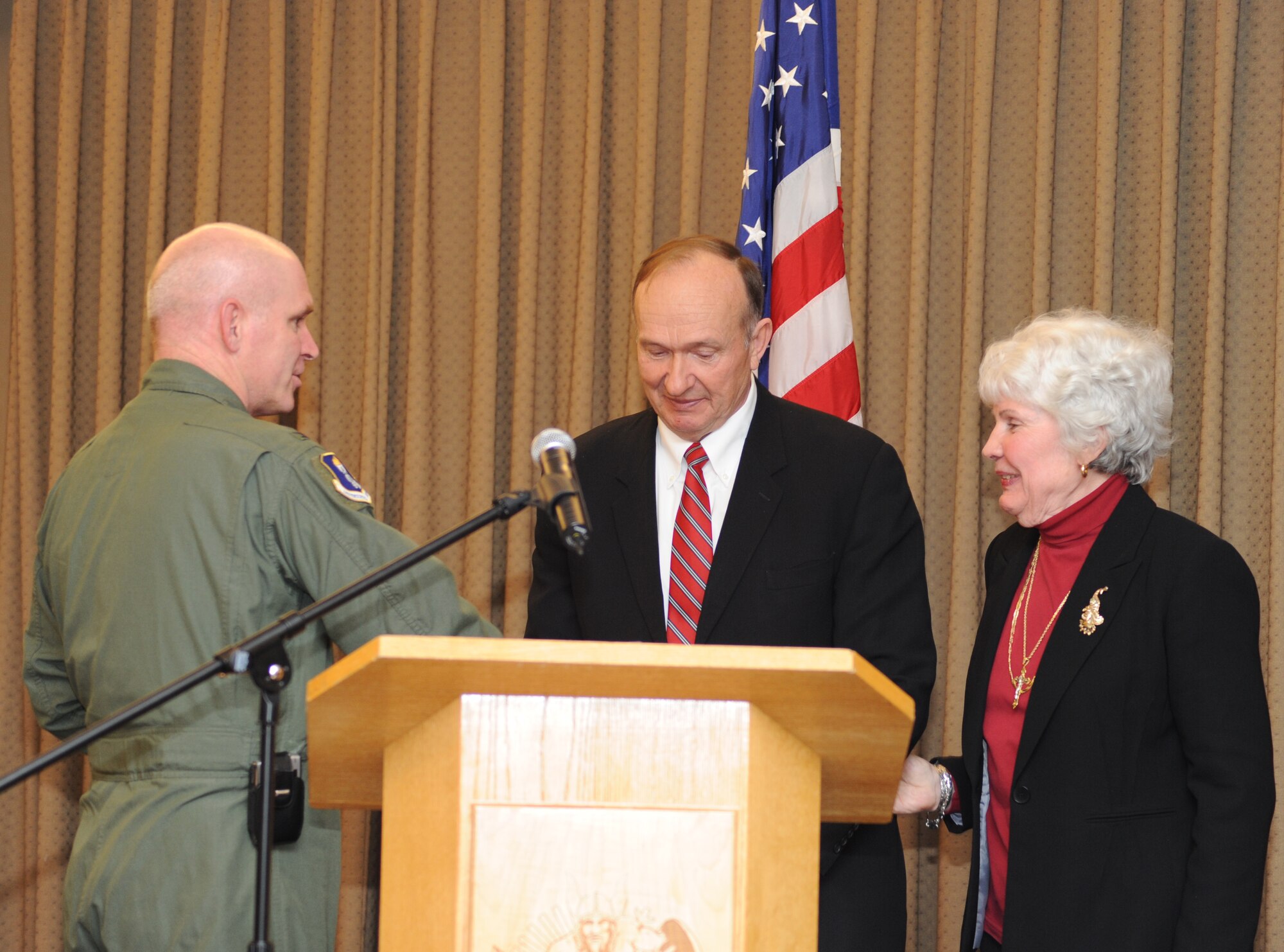 Col. John M. Quinn, 319th Air Refueling Wing vice-commander, presents retired U.S. Air Force Capt. Guy D. Gruters and his wife Sandy coins during a luncheon held at Grand Forks Air Base, North Dakota Mar. 8. Capt. Gruters and a fellow pilot were shot down Dec. 21, 1967 and subsequently captured by the enemy during the Vietnam War. The two Airmen were taken to a small prison where encountered Air Force Medal of Honor winner, Capt. Lance P. Sijan. They were held there one week before being transported to the Hanoi Hilton. He and his fellow Prisoners of War were released in March 1973. He and his wife Sandy travel around the United States to various military installations spreading the message of faith in captivity. (U.S. Air Force photo/Airman 1st Class Amber Price)