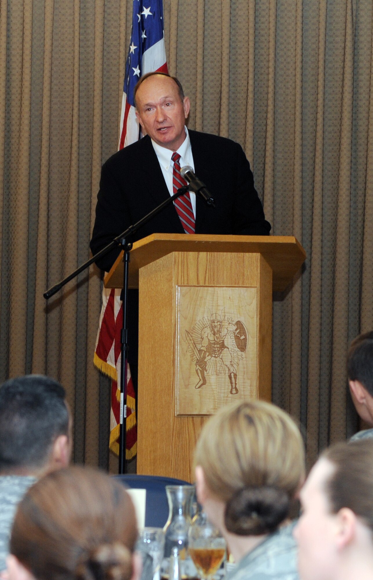 Retired U.S. Air Force Capt. Guy D. Gruters speaks to more than 150 Airmen during a luncheon held at Grand Forks Air Force Base, North Dakota March 8. Capt. Gruters and a fellow pilot were shot down Dec. 21, 1967 and subsequently captured by the enemy during the Vietnam War. The two Airmen were taken to a small prison where they first encountered Air Force Medal of Honor winner, Capt. Lance P. Sijan. They were held there one week before being transported to the Hanoi Hilton. He and his fellow Prisoners of War were released in March 1973. He and his wife Sandy travel around the United States to various military installations spreading the message of faith in captivity. (U.S. Air Force photo/Tech Sgt. Johnny Saldivar)