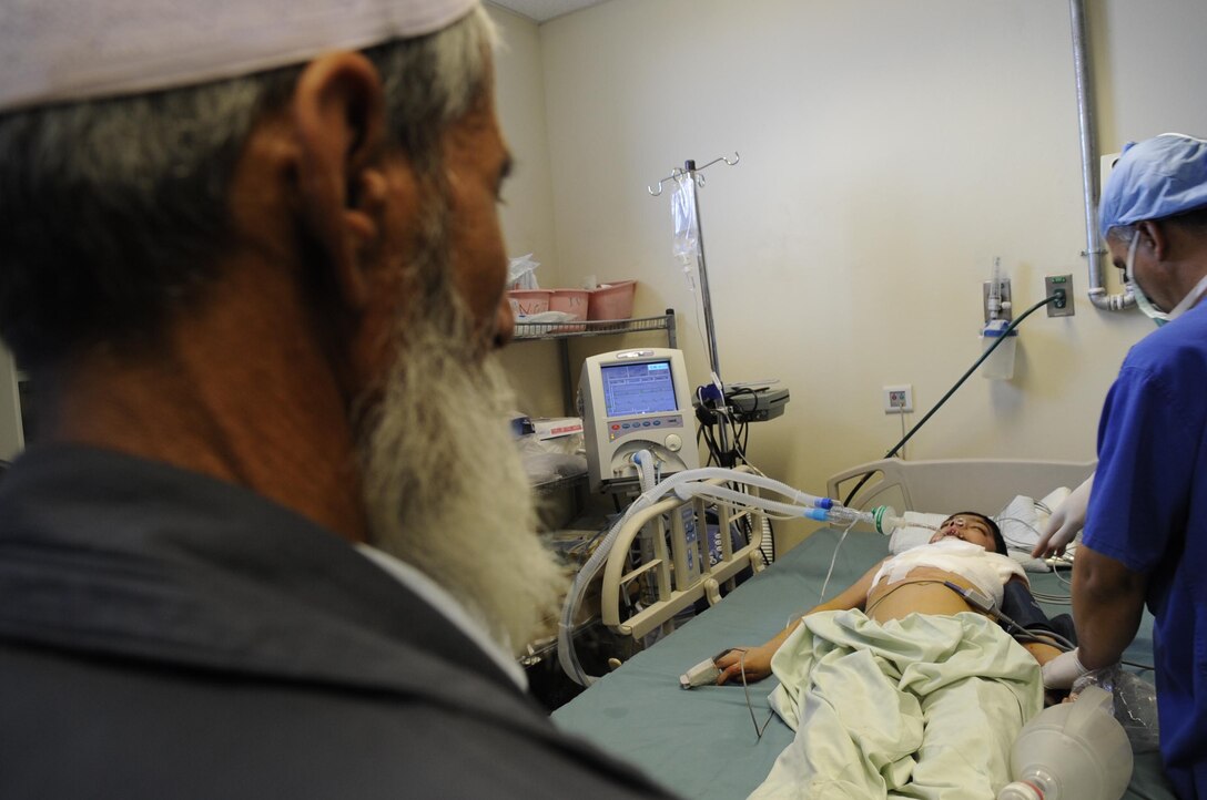 Abdul Ghafer waits patiently for his son, Abdul Rahman, recovery after having surgery on his neck March 1 at the Kandahar Regional Military Hospital.  The patient only 13 years old burned himself cooking five months ago.  Col. Barry Steinberg assisted in the surgery.  (U.S. Air Force photo by Senior Airman Nancy Hooks/Released)