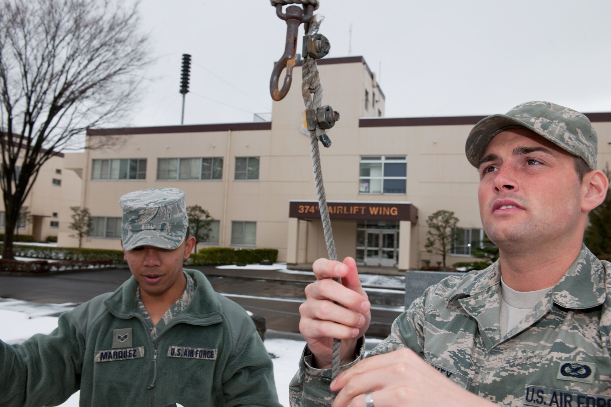YOKOTA AIR BASE, Japan -- Senior Airman Mario Marquez (left) and Airman 1st Class Devin Doskey, both from the 374th Airlift Wing, secure the American flag March 10. Airman Marquez and Airman Doskey raised and lowered the flag for the base honor guard. The American flag is presented to Airmen upon retirement and symbolizes their service to the United States. (U.S. Air Force photo/Osakabe Yasuo)