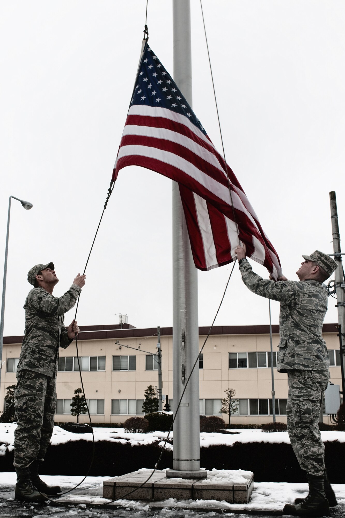 YOKOTA AIR BASE, Japan -- Airman 1st Class Devin Doskey and Airman 1st Class Sean Martin, both from the 374th Airlift Wing, raise the American flag March 10. Airman Doskey and Airman Martin raised the flag for the base honor guard. The American flag is presented to Airmen upon retirement and symbolizes their service to the United States. (U.S. Air Force photo/Osakabe Yasuo)