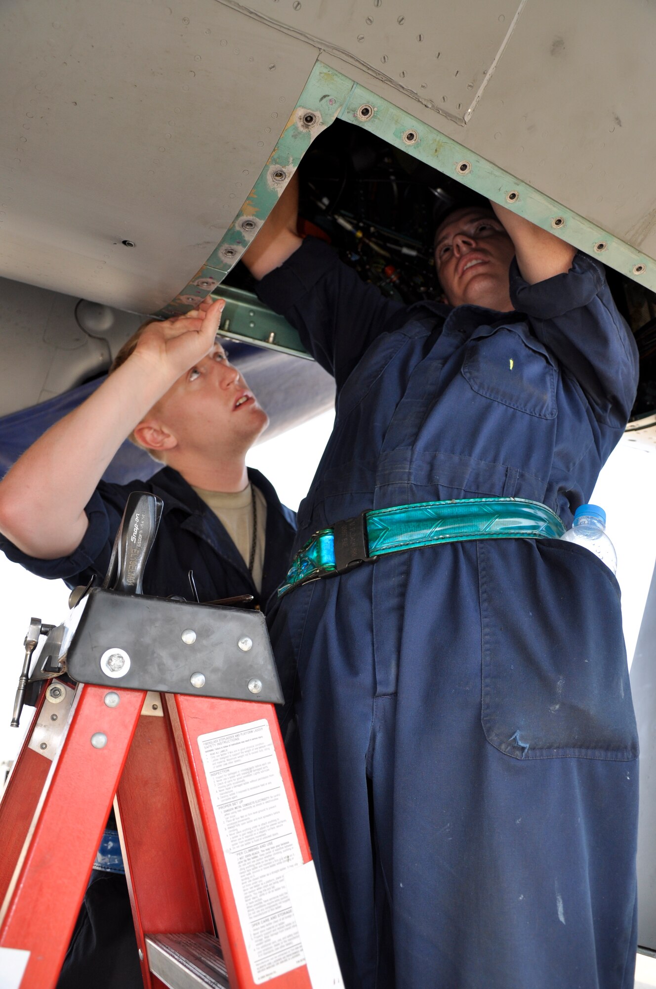 Senior Airman Nick Vogel (left) watches and learns as Senior Airman Matthew Bujanauski replaces a duct in the air conditioning bay of a U.S. Air Force F-15 Eagle at Korat Royal Thai Air Force Base, Thailand, that is participating in exercise Cope Tiger 2010, March 9.  Both Airmen are from the 19th Aircraft Maintenance Unit at Elmendorf Air Force Base, Alaska, and are participating in Cope Tiger 2010, a multilateral aerial large-force exercise involving U.S., Singapore and Thai air forces. The exercise enhances combined readiness and interoperability between the United States and countries throughout the Asia-Pacific region. (U.S. Air Force photo/Capt. Christy Stravolo)
