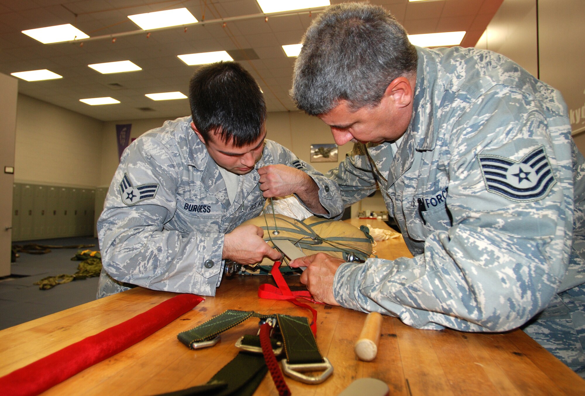 PATRICK AIR FORCE BASE, Fla. - Senior Airmen Jarrod Burgess and Tech. Sgt. Darryl Perron work together to stuff the parachute back in its original casing. Usually packing a parachute is a one-man job,but for this case, two sets of hands sped up the process. (U.S. Air Force Photo/Staff Sgt. Leslie Kraushaar)