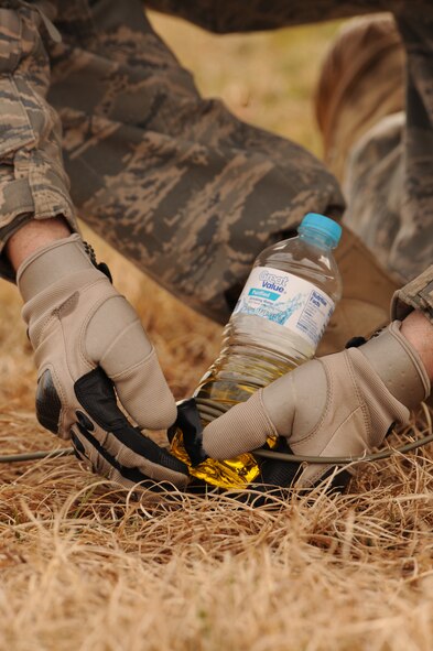 Senior Airman Cooper Gibson, 4th Civil Engineer Squadron explosive ordnance disposal technician, tapes detonation cord to a fuel-filled water bottle on Seymour Johnson Air Force Base, N.C., March 4, 2010. The cord can detonate multiple charges simultaneously regardless of the distance from the initiation point. Gibson hails from Friendswood, Texas. (U.S. Air Force photo/Staff Sgt. Courtney Richardson)