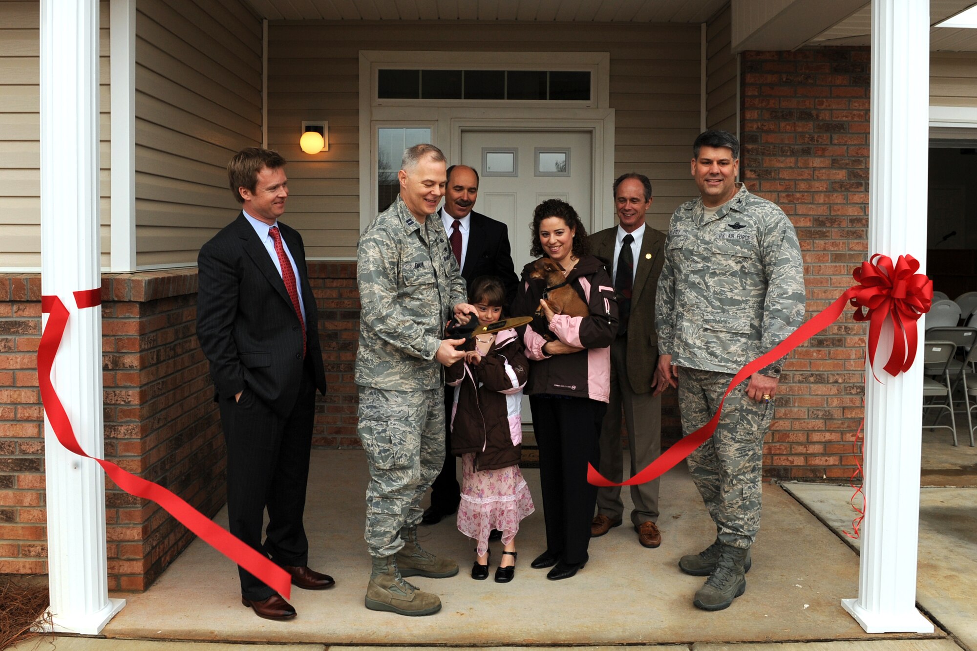 Capt. Daniel Dahl, 19th Force Support Squadron, his daughter, Jordan, and wife, Amy, cut the ribbon March 9 to their new housing unit at Little Rock Air Force Base. The family was joined at the ribbon-cutting ceremony by Brad Reisinger, Pinnacle Development Company vice president, Robin Vaughn, Hunt Development Group president, the Honorable Gary Fletcher, mayor of the City of Jacksonville, and Col. Greg Otey, 19th Airlift Wing commander. (U.S. Air Force photo by Senior Airman Ethan Morgan)
