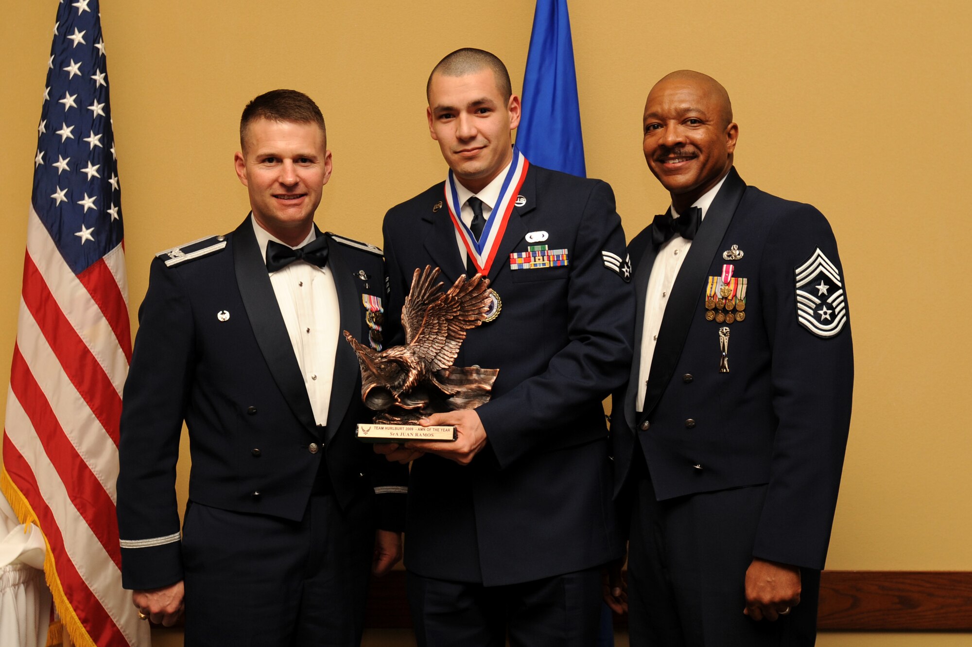 Senior Airman Juan Ramos, 68th Network Warfare Squadron, center, accepts the airman annual award from Col. Greg Lengyel, 1st Special Operations Wing commander, and Chief Master Sgt. Dexter Mitchell, 1st SOW command chief, at the 2009 Annual Team Hurlburt Awards Banquet at the Hurlburt Field Soundside Club Mar. 4. (U.S. Air Force photo by Senior Airman Matthew Loken)