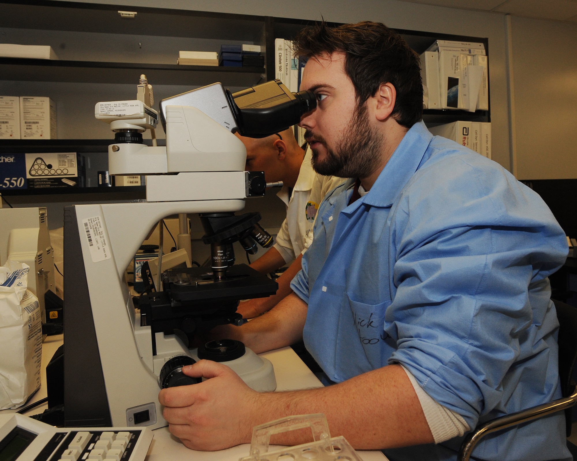 Nicklaus Hoover, 19th Medical Group medical technician, and Airman 1st Class Grant Wendland, 19th Medical Group medical technician, view a blood sample on a microscope slide Feb. 26. Mr. Hoover and Airman Wendland are identifying and verifying abnormalities seen on a microscope slide helping in diagnosing patient conditions. (U.S. Air Force photo by Staff Sgt. Chad Chisholm)