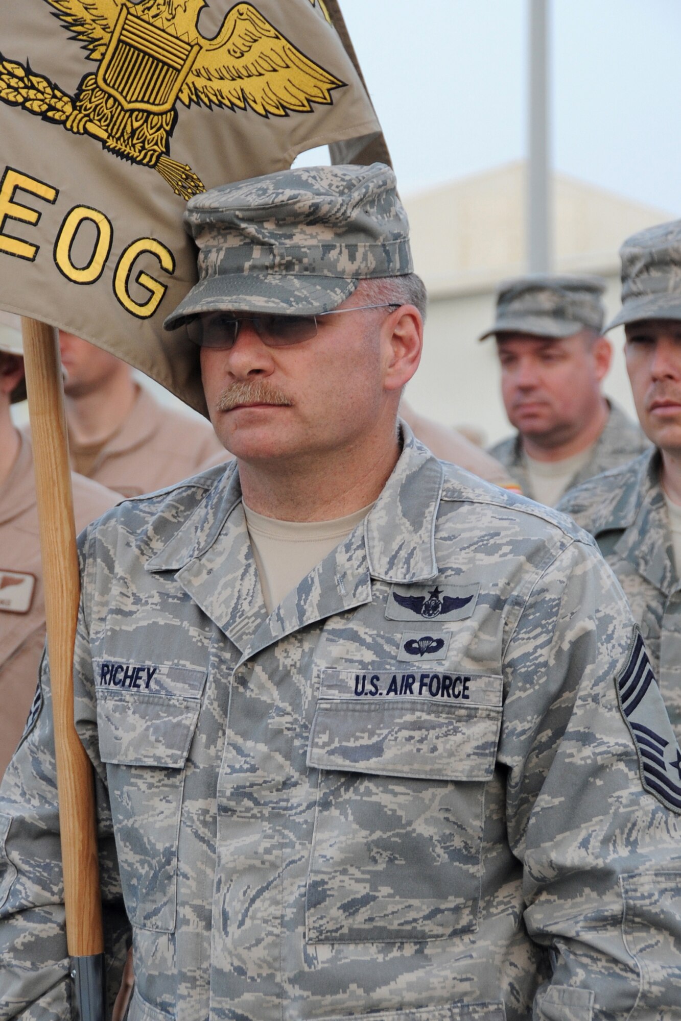 Chief Master Sgt. Bruce Richey, 380th Expeditionary Operations Group Chief Enlishted Manager, holds the guidon during retreat at an undisclosed location in Southwest Asia on March 5, 2010.  Airmen from across the wing join every week to pay respect during retreat. The 380th Air Expeditonary Wing supports Operations Iraqi Freedom and Enduring Freedom and the Combined Joint Task Force-Horn of Africa. The 380th AEW is comprised of four groups and 12 squadrons and the wing's deployed mission includes air refueling, surveillance and reconnaissance in support of overseas contingency operations in Southwest Asia.(U.S. Air Force photo/Senior Airman Jenifer H. Calhoun/Released)
