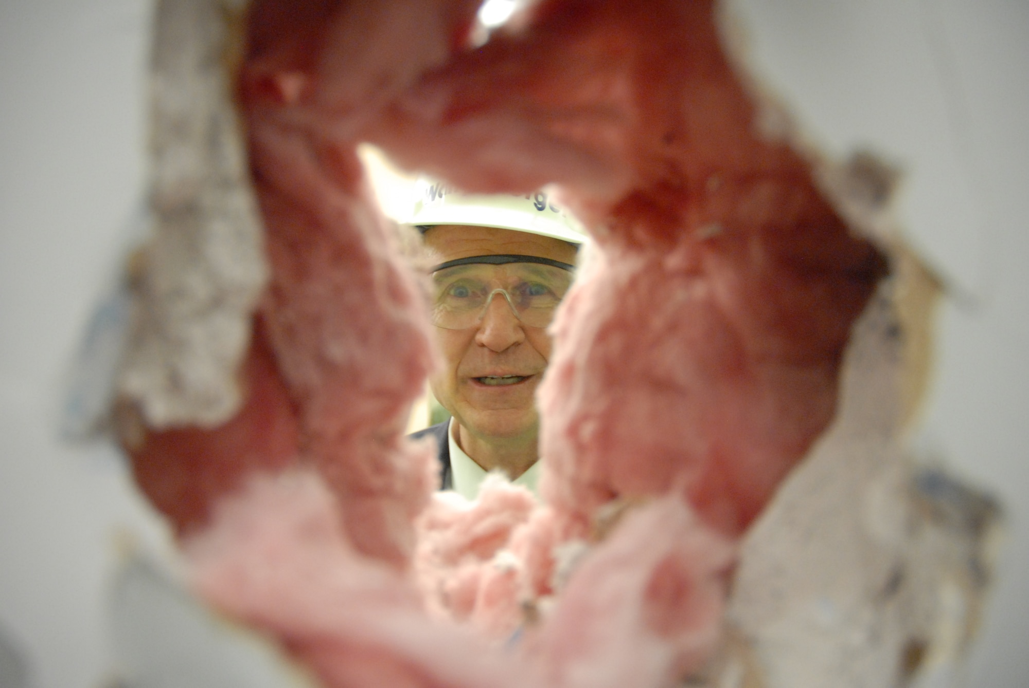 U.S. Rep. Wally Herger peers through a hole in the wall of an office within the 713th Combat Operations facilities at Beale Air Force Base, Calif.  The California District 2 congressman joined 940th Wing Commander, Colonel Jeffrey Mineo, 9th Reconnaissance Wing Commander, Colonel Robert Yahn, and Reservists of the 713 COS in a ceremonial "wall bashing" to mark the start of a renovation project planned to accommodate the increasing reachback capabilities of the 713 COS in support of Pacific Air Forces missions. (U.S. Air Force Photo/Tech. Sgt. Kenneth McCann)