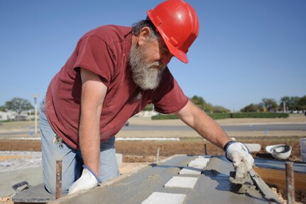 Bobby Pogue, 902nd Civil Engineer Squadron cement finisher, smoothes out newly-poured concrete during the replacement of the Randolph Field letters facing Washington Circle March 11. (U.S. Air Force photo by Steve Thurow)