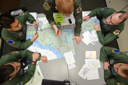 Combat system officer students from the 562nd Flying Training Squadron, C-flight, at Randoph Air Force Base, TX, listen as their instructor goes over the simulated flight path on a navigation chart prior to a systems navigation simulator flight where they will learn to recognize and communicate weather and altitude hazards. (U.S. Air Force photo/Steve Thurow)