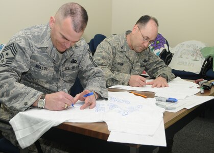 ALTUS AIR FORCE BASE, Okla.-- Colonel Stu Shaw, 97th Air Mobility Wing vice commander, and Chief Master Sergeant Eric Molloy, 97th AMW command chief, decorate t-shirts to support sexual assault prevention throughout the Air Force March 3. Squadrons from all over the base participated in decorating these t-shirts that will be displayed at the Pentagon, Washington D.C. (U.S. Air Force photo / Senior Airman Cherice Bryant)   