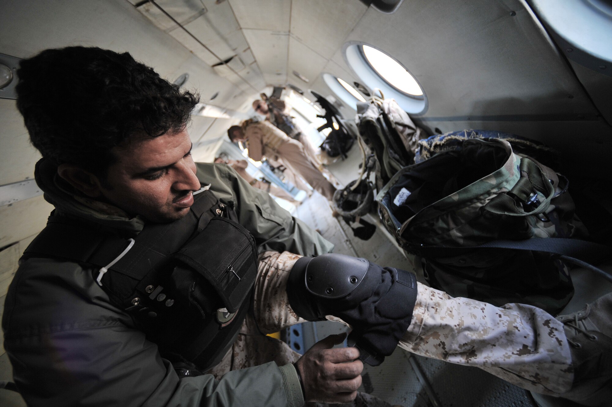 An Iraqi Mi-17 helicopter aerial gunner dons his knee pads before engine-start March 2, 2010, at Camp Taji, Iraq. (U.S. Air Force photo/Staff Sgt. Quinton Russ)
