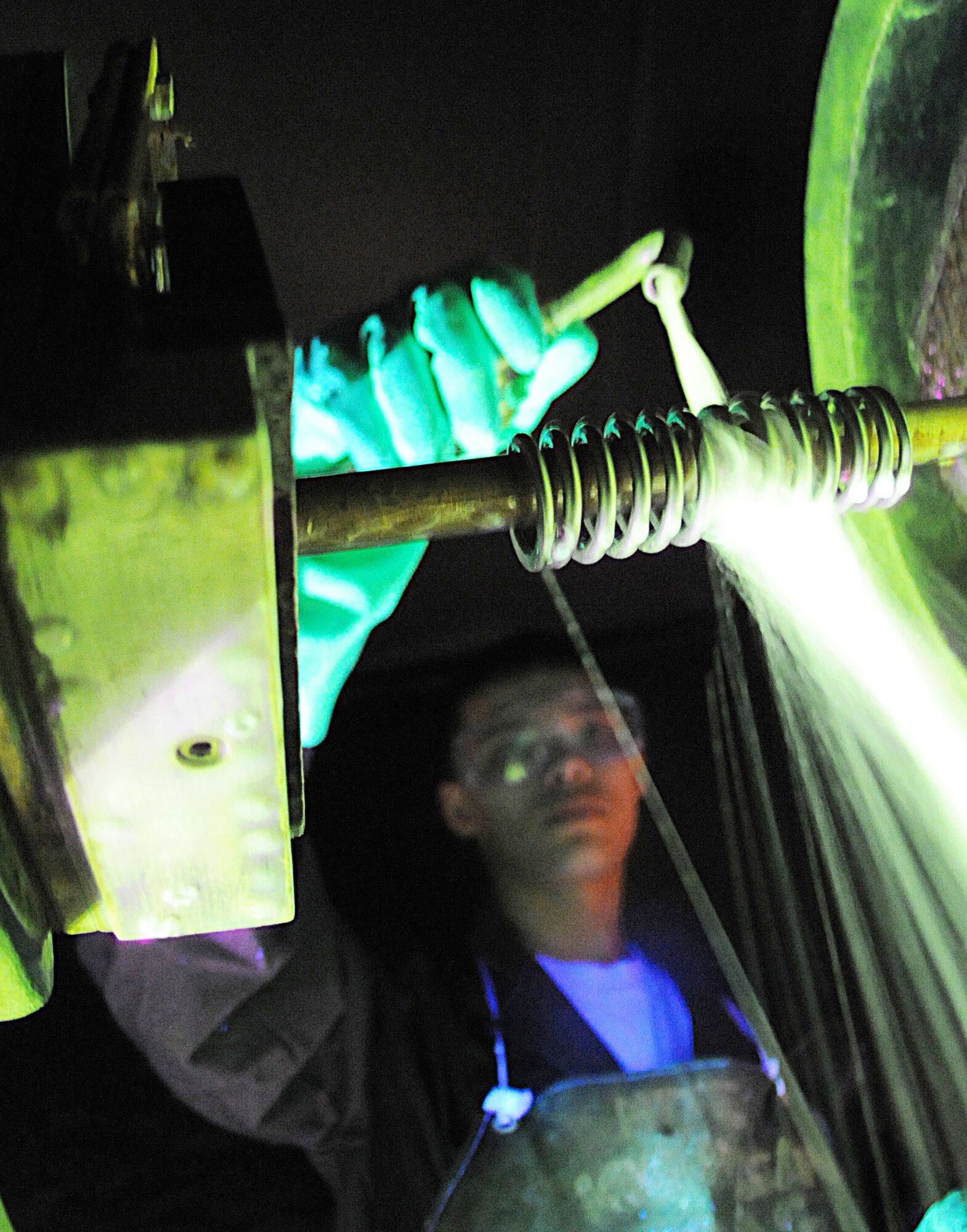 At the non-destructive inspection shop, Airman 1st Class Christopher Bovill pours a microscopic iron solution over a spring inside a magnetic particle machine March 9, 2010, at RAF Mildenhall, England.  Airman Bovil is a NDI technician with the 100th Maintenance Group. (U.S. Air Force photo/Staff Sgt. Jerry Fleshman)