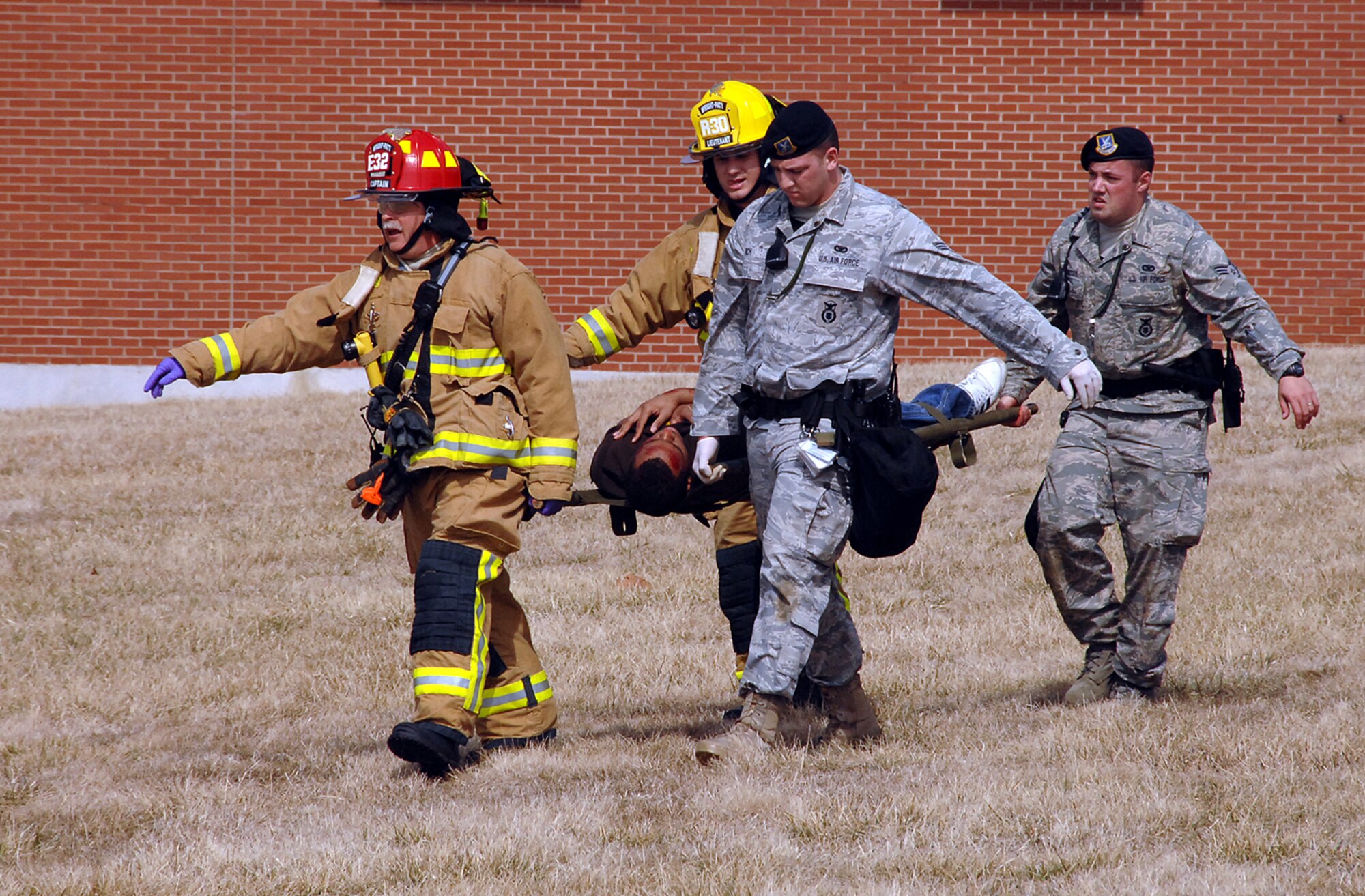 First responders rescue, triage and prepare the injured for transport during a mass casualty exercise March 10, 2010 at Wright-Patterson Air Force Base, Ohio. The scenario included a tornado touchdown near Building 79 in Area B, which also struck people exiting a bus who were attempting to seek shelter. Pictured (from left) are Wright-Patterson firefighters Captain Matthew Nethers and Lieutenant Samuel Feltner, and 88th Security Forces Squadron members Senior Airman Tyler Rich and Staff Sgt. Jerrod Ricketts.  (U.S. Air Force photo/Ben Strasser)