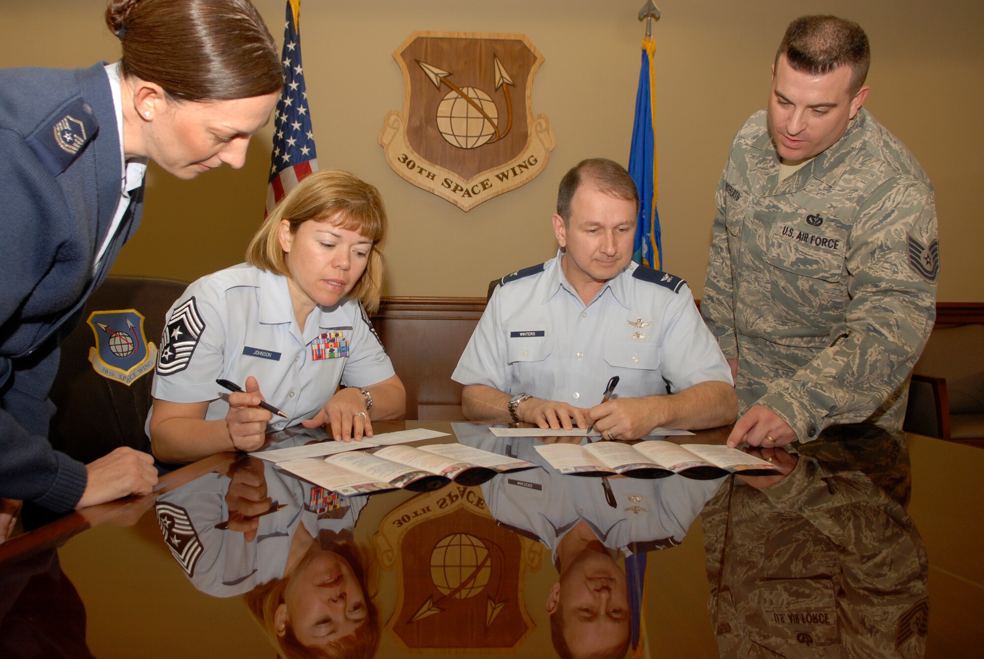 VANDENBERG AIR FORCE BASE, Calif. -- Col. Steven Winters, the 30th Space Wing vice commander, and Chief Master Sgt. Angelica Johnson, the 30th SW command chief, fill out forms for the Air Force Assistance Fund here Monday, March 8, 2010.  Master Sgt. Blenda Mease, the 30th SW assistant installation AFAF project manager, and Tech. Sgt. Adam Roberts, a 30th SW AFAF manager, assisted the base leadership by pointing out the areas where their donations will go to help Airmen and their families. (U.S. Air Force photo/Senior Airman Andrew Satran) 