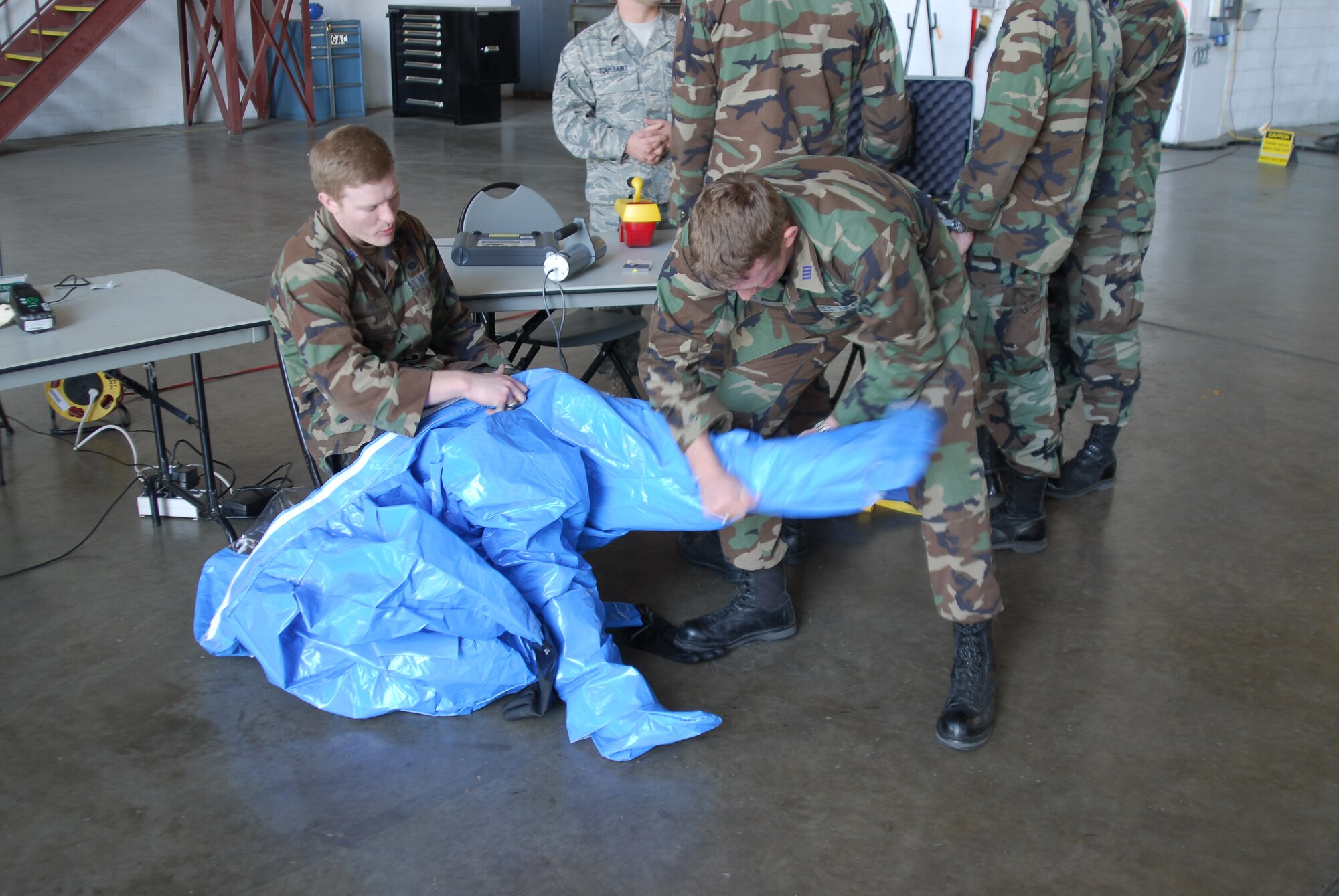 Cadet 1st Class Cameron Rochelle, 19th Cadet Squadron at the U.S. Air Force Academy, Colo., dons a bioenviromental hazards material training suit with the assistance of Cadet 1st Class Cody Hanson during an operations fair held at Hangar 250 Saturday. During the fair, cadets met Team Little Rock members from base operations, maintenance, mission support, and medical groups. The cadets also toured a C-130 on the flightline and viewed C-130s undergoing maintenance inspections at Hangar 250. The 19th Airlift Wing is the 19th Cadet Squadron's sponser wing. (U.S. Air Force photo by Staff Sgt. Juan Torres)