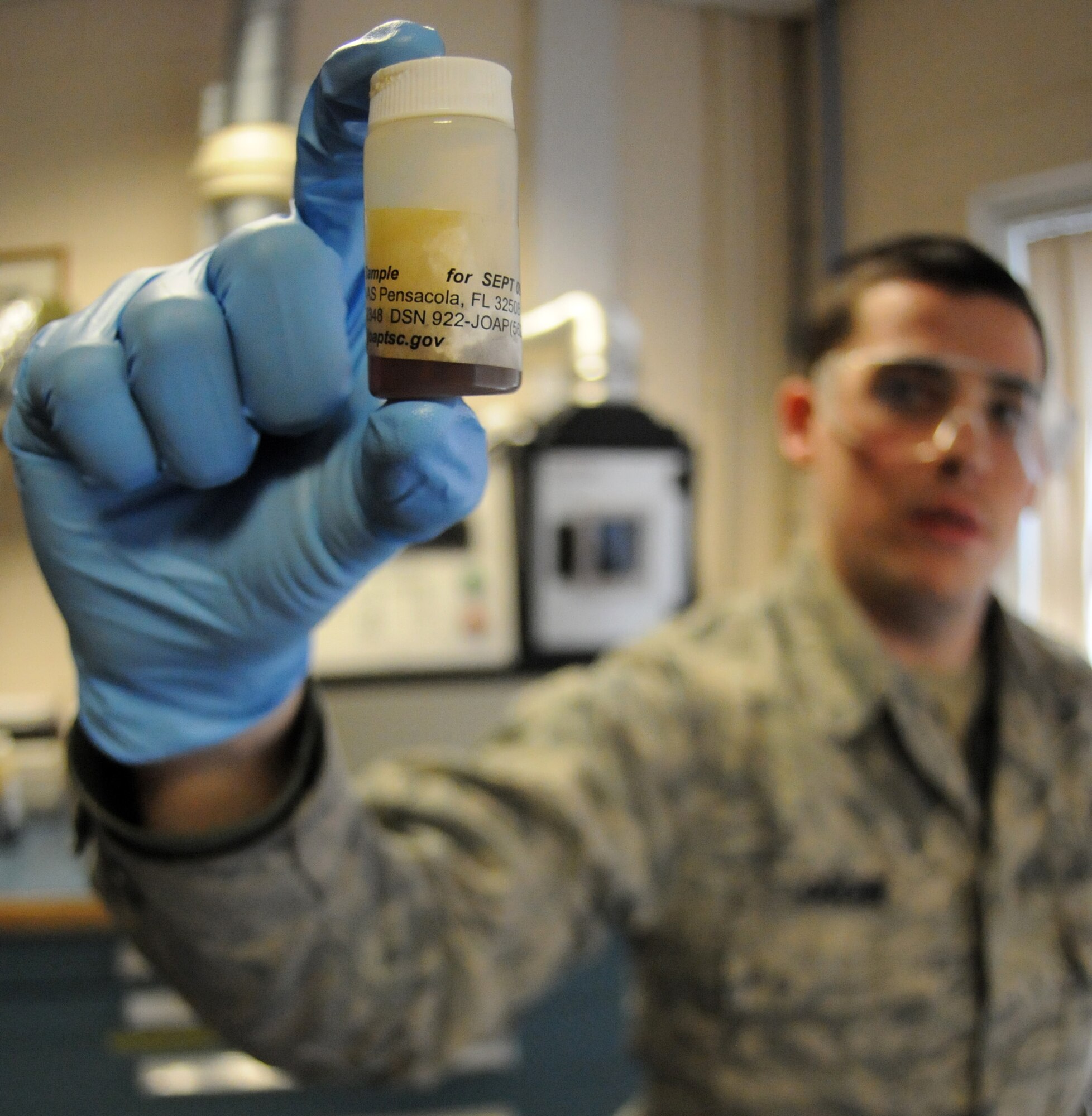 RAF MILDENHALL, England – Airman Josh Ouchie, 100th Maintenance Group Non-Destructive Inspection technician, holds up a bottle of aircraft engine oil prior to running it through Spectral M machine at the NDI shop March 9. The machine measures all “wear” metal inside the oil sample breaking it down to parts per millionth to help determine if aircraft engines are within acceptable operating limits. If metal particles exceed the allowable limits, further troubleshooting is involved to locate the failing part or parts preventing possible damage to or loss of aircraft. (U.S. Air Force photo/ Staff Sgt. Jerry Fleshman)