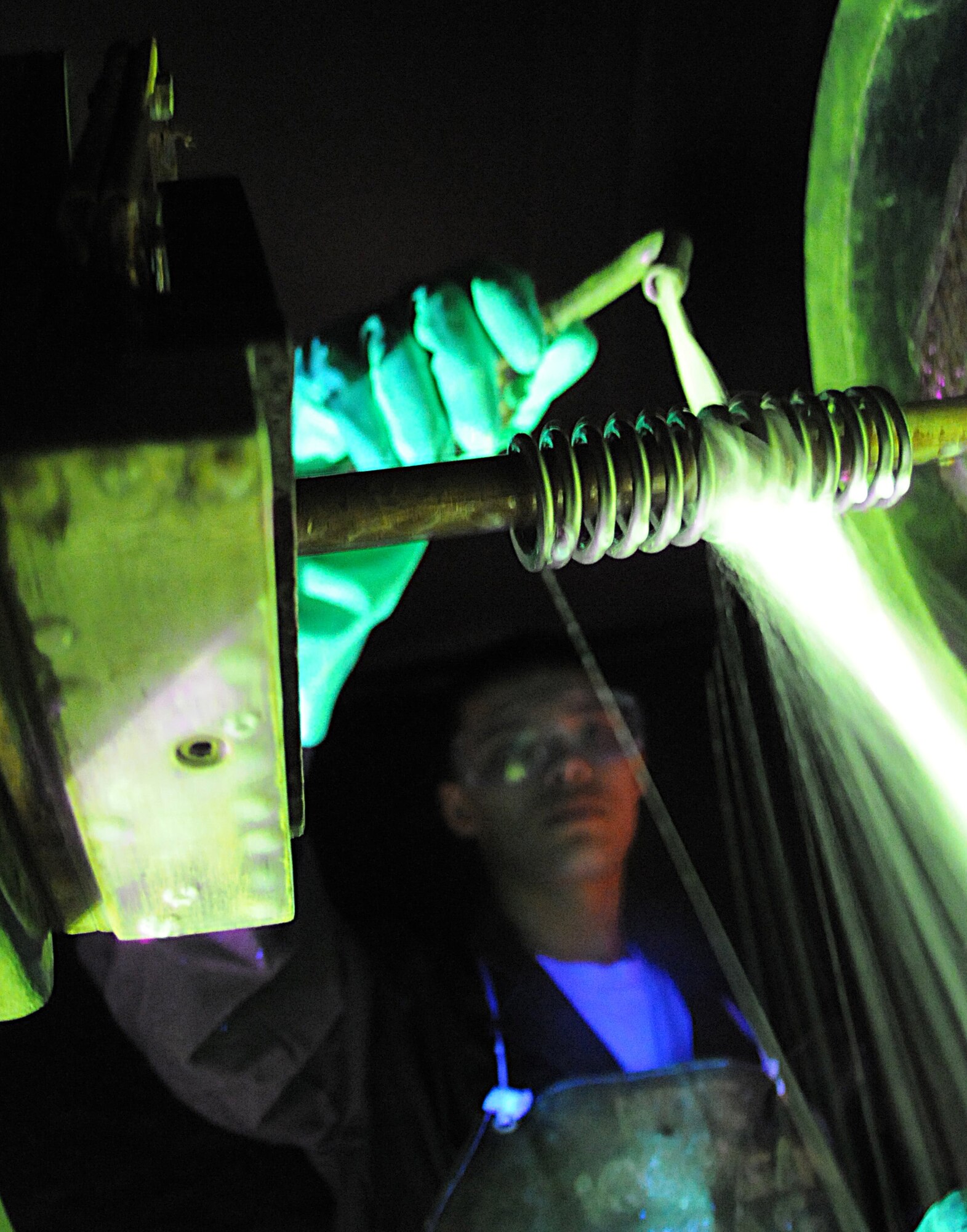 RAF MILDENHALL, England – Airman 1st Class Christopher Bovill, 100th Maintenance Group Non-Destructive Inspection technician, pours a microscopic iron solution over a spring inside a magnetic particle machine at the NDI shop March 9. (U.S. Air Force photo/ Staff Sgt. Jerry Fleshman)