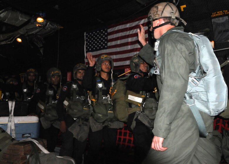 OVER PHNOM PENH, Kingdom of Cambodia -- A jumpmaster from the U.S. Army Special Forces high fives Royal Cambodian Armed Forces National Counter-Terrorism Special Forces members before they parachute from the back of a MC-130P Combat Shadow here Feb. 22. More than 90 U.S. and RCAF soldiers combined to mark the first-ever combined airdrop between U.S. and Cambodian forces. It was also the first-ever airdrop for NCTSF soldiers. (U.S. Air Force photo by Tech. Sgt. Aaron Cram)