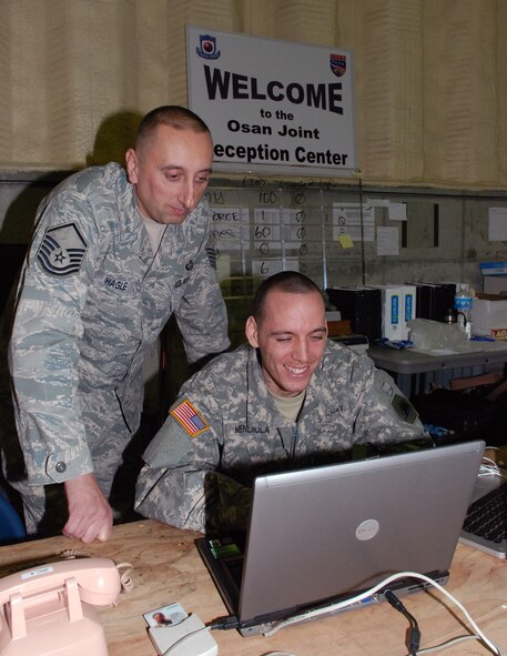 Master Sgt. Scott Hagle, Osan Joint Reception Center noncommissioned officer in charge, and Army Spc. Howard Mendiola, JRC clerk, update the JRC personnel database March 11 at Rush Park at Osan Air Base, South Korea. (U.S. Air Force photo/Staff Sgt. Steve Grever)