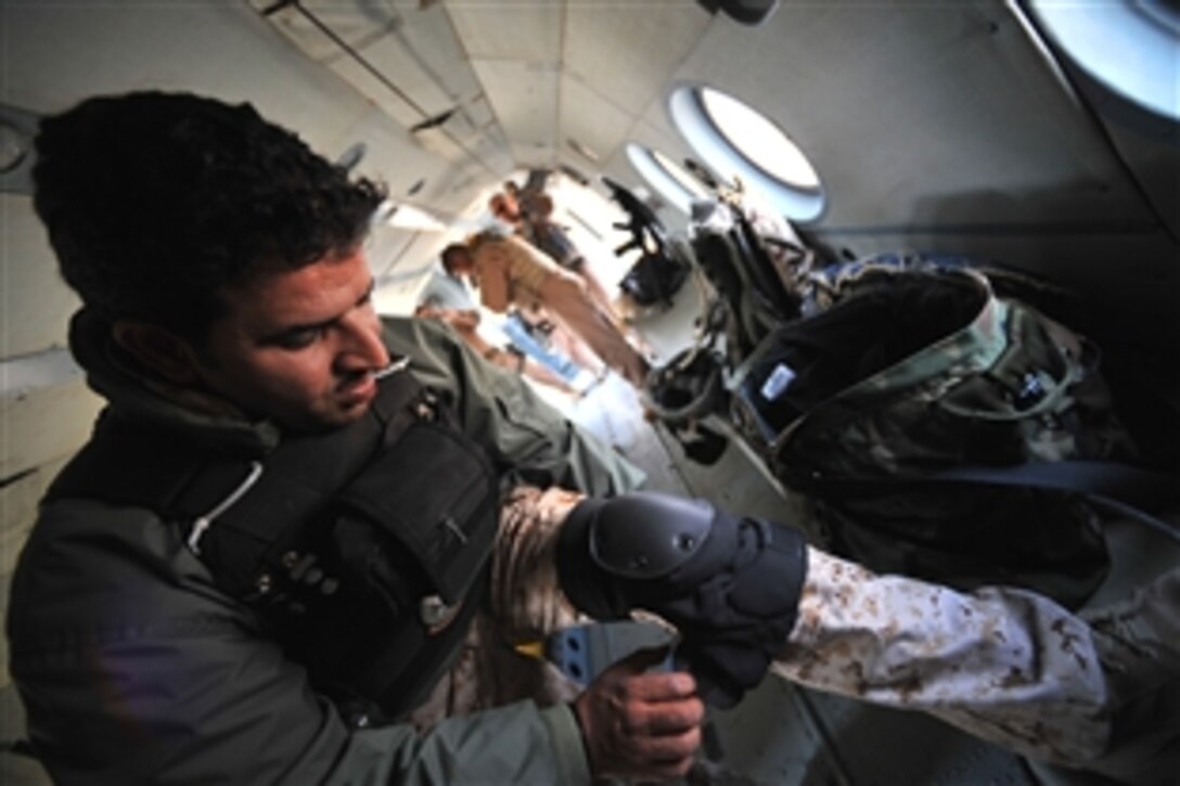 An Iraqi Mi-17 helicopter aerial gunner dons knee pads before engine-start to prepare for flight at Camp Taji, Iraq, March 2, 2010. The Iraqi gunners progress from students led by U.S. instructors to leading students themselves. U.S. instructors conduct surprise inspections to assess how well their former students take the lead.

