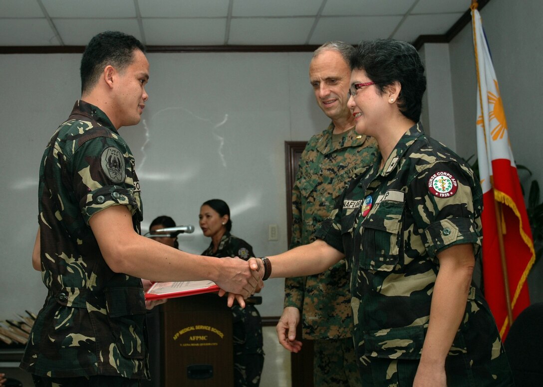 Brigadier Gen. Nelia Buenaflor, the Chief Nurse of the Armed Forces of the Philippines Nurse Corps(right) and U.S. Navy Capt. Robert Hunter (center) present a certificate of attendance to AFP 1st Lt. Rozano Goricho at the conclusion of the 2nd Annual Professional Nursing Symposium March 12, 2010, during Balikatan 2010. The symposium was conducted as a joint effort between AFP nurses, U.S. civilians and selected medical personnel from the 3rd Marine Logistics Group, III Marine Expeditionary Force, and 4th Marine Air Wing. Balikatan is an annual bilateral exercise with the AFP, Philippine civil defense agencies and U.S. military designed to increase interoperability and security in the region. The exercise includes humanitarian operations and training exercises. (Official U.S. Navy photo by Chief Petty Officer David M. Votroubek)