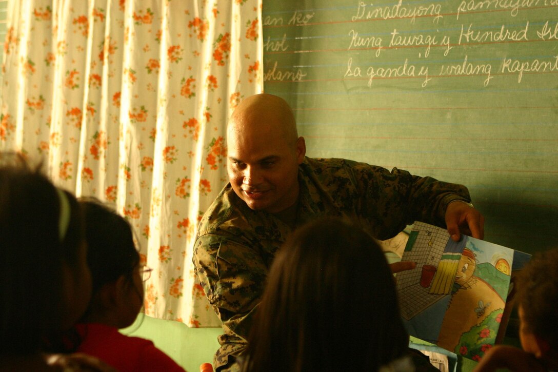 Staff Sgt. Alberto Oliveras, motor-transport maintenance chief for Combat Logistics Battalion 31 (CLB-31), 31st Marine Expeditionary Unit (MEU), reads to students from St. Juliana Elementary School during a community relations (COMREL) event, March 12. CLB-31 took an operational pause during exercise Balikatan 2010 (BK ’10) to build bridges of friendship with the local community.