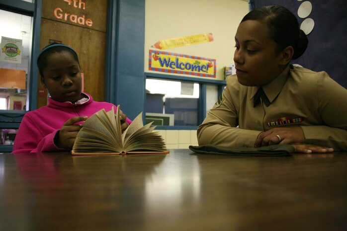 ::r::::n::Cpl. Chantal A. Jarmond, a supply clerk with Marine Tactical Air Command Squadron 28, reads a book with Tykeriah Reeves, a fourth-grade student at Roger Bell Elementary School, March 11, as part of the Adopt-A-School program. The program allows Cherry Point units to partner with local schools.::r::::n::