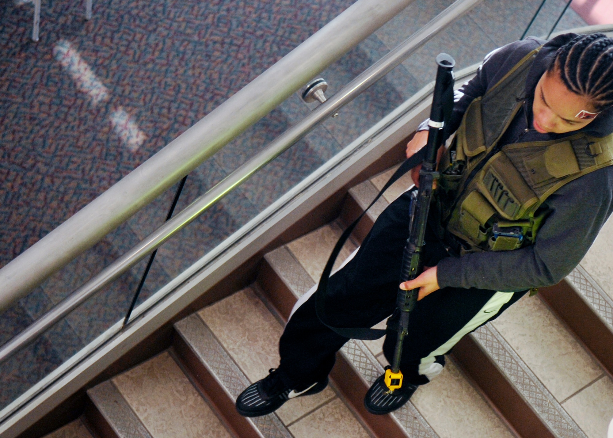 HOLLOMAN AIR FORCE BASE, N.M. -- Senior Airman Lauren Moss, 49th Aeromedical Dental Squadron, plays an active shooter running down the stairs at the Domenici Fitness and Sports Center, March 11, 2010, during exercise Coronet Gold Rush 10-02. The scenario for the active shooter exercise involved two active gunmen who indiscriminately targeted individuals at the fitness center during hours of operation. The goal of the exercise was to evaluate how well Team Holloman is prepared for an active shooter scenario on the installation. (U.S. Air Force photo by Staff Sgt. Anthony Nelson Jr.)