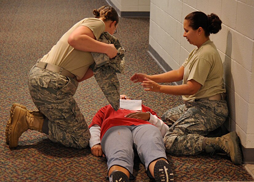 HOLLOMAN AIR FORCE BASE, N.M. -- Members from Team Holloman perform self aid and buddy care on a woman who suffered a simulated gunshot wound at the Domenici Fitness and Sports Center, March 11, 2010, during exercise Coronet Gold Rush 10-02. The active shooter exercise involved all members of Team Holloman. The goal of the exercise was to evaluate how well Team Holloman is prepared for an active shooter scenario on the installation.  (U.S. Air Force photo by Staff Sgt. Anthony Nelson Jr.)