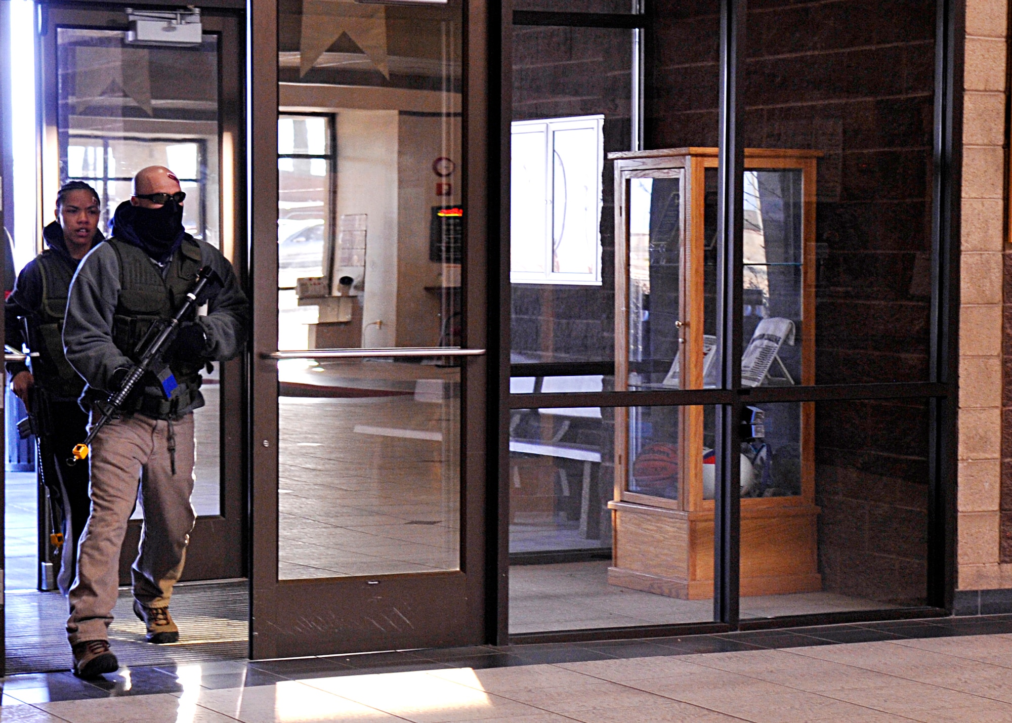 HOLLOMAN AIR FORCE BASE, N.M. -- Two armed gunmen, played by Tech. Sgt. David Loera, 49th Material Maintenance Group and Senior Airman Lauren Moss, 49th Aeromedical Dental Squadron, enter the Domenici Fitness and Sports Center, March 11, 2010, during exercise Coronet Gold Rush 10-02. The active shooter exercise involved all members from Team Holloman. The goal of the exercise was to evaluate how well Team Holloman is prepared for an active shooter scenario on the installation. (U.S. Air Force photo by Staff Sgt. Anthony Nelson Jr.)