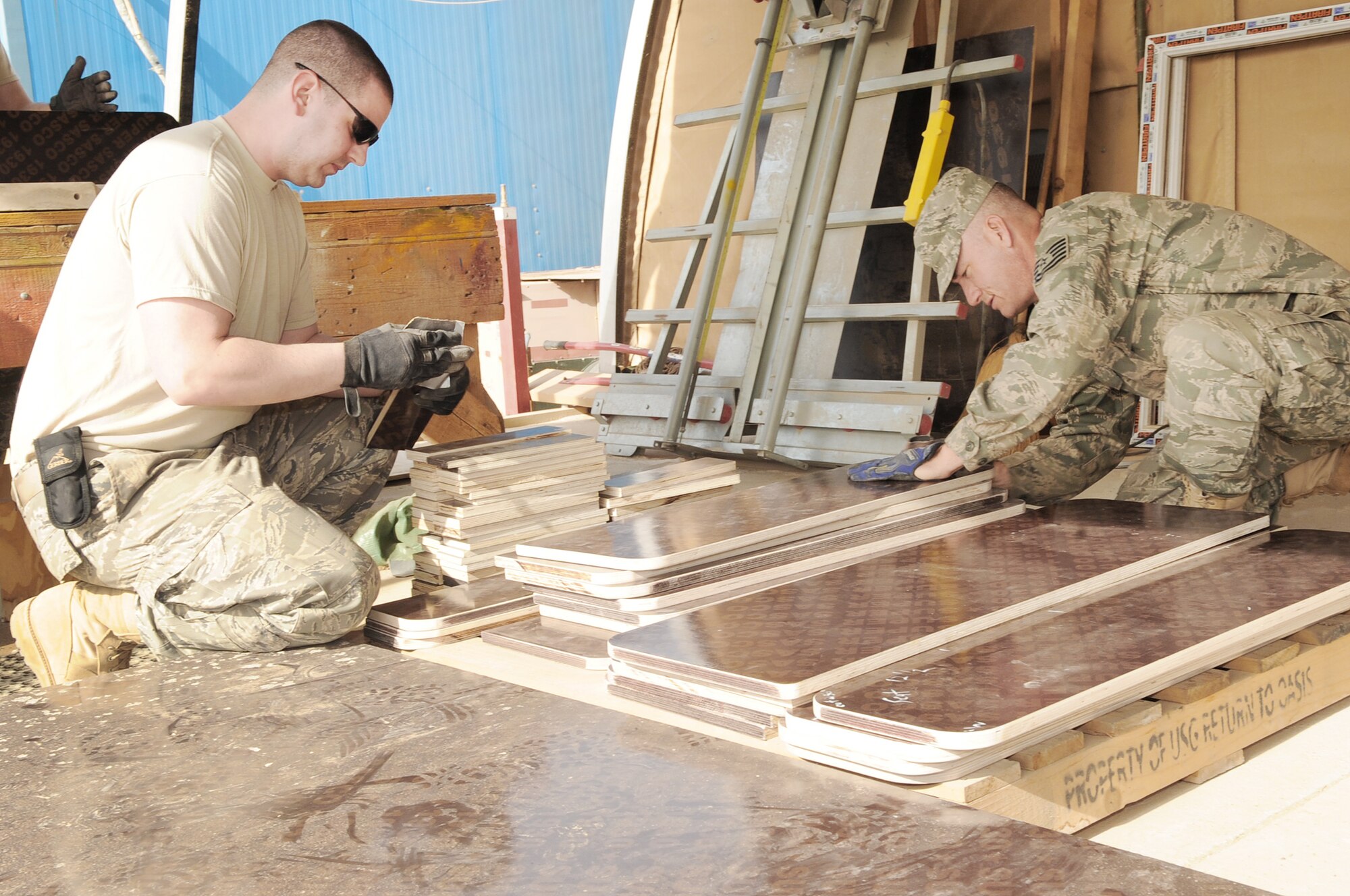 Volunteers from the 506th Expeditionary Civil Engineer Squadron sand down pieces of wood during assembly of school desks for local Iraqi children March 6, 2010, at Kirkuk Regional Air Base, Iraq. (U.S. Air Force photo/Staff Sgt. Tabitha Kuykendall