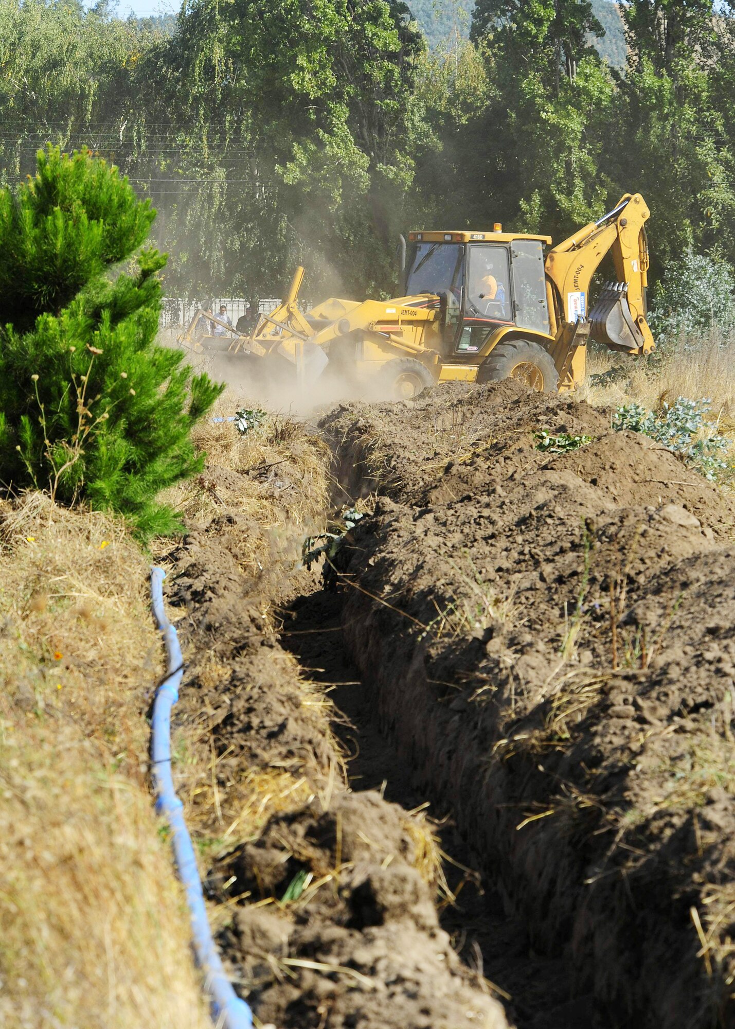 Chilean construction workers use a backhoe to cover the water pipes laid just three days ago March 10, 2010, in Angol, Chile. Chileans laid water and electrical pipes that will lead to the Air Force Expeditionary Medical Support site. (U.S. Air Force photo/Senior Airman Tiffany Trojca)
