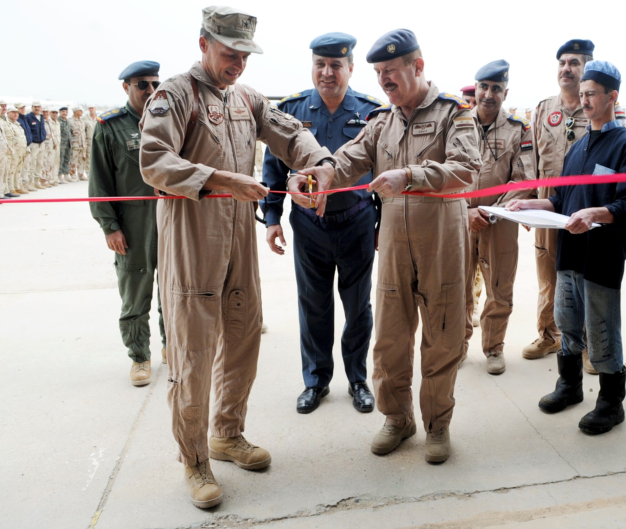 Members of the Iraq Training and Advisory Mission, U.S. Air Force and the Iraqi air force, stand shoulder to shoulder during a ribbon cutting ceremony on Kirkuk Regional Air Base, Iraq on March 10, 2010.  Brig. Gen. Scott Hanson, 321st Air Expeditionary Wing commander, and Staff Lt. Gen. Anwer Ameen, Iraqi air force commander, signed a letter of acceptance and transfer for the newly restored Skeleton Hangar. (U.S. Air Force photo/Staff Sgt. Tabitha Kuykendall/Released)