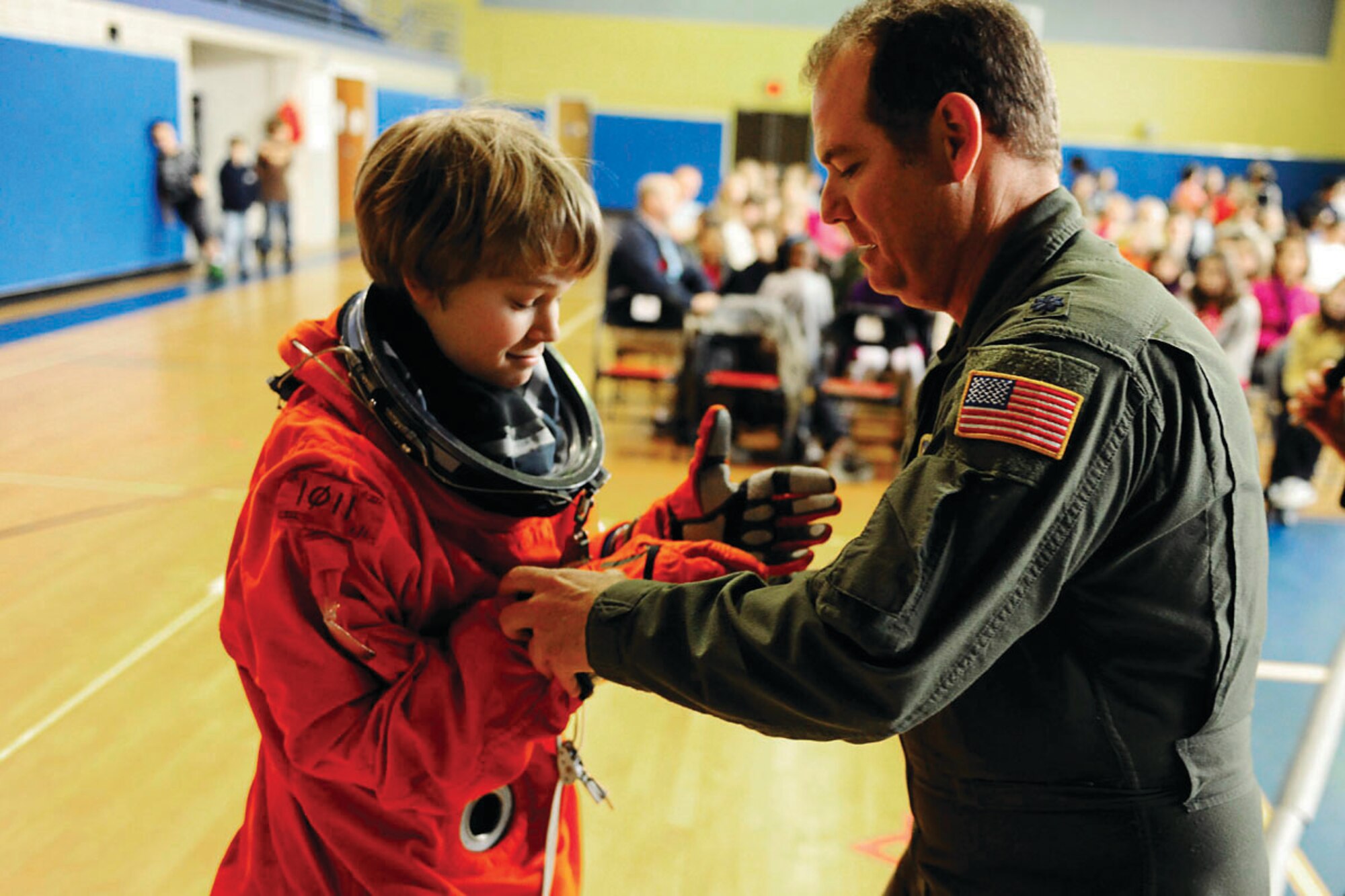 Lt. Col. Rob Lindsay, a space shuttle contingency support officer from Patrick Air Force Base, Fla., assists Daniel Benedict, 14, son of Maj. Colby Benedict, with putting on a space suit at Lajes High School on March 3. Lt. Col. Lindsay, who was at Lajes as part of a space shuttle emergency landing exercise, visited the school to talk to kids about the U.S. space program. (U.S. Air Force photo by Tech. Sgt. Darrell Dean)
