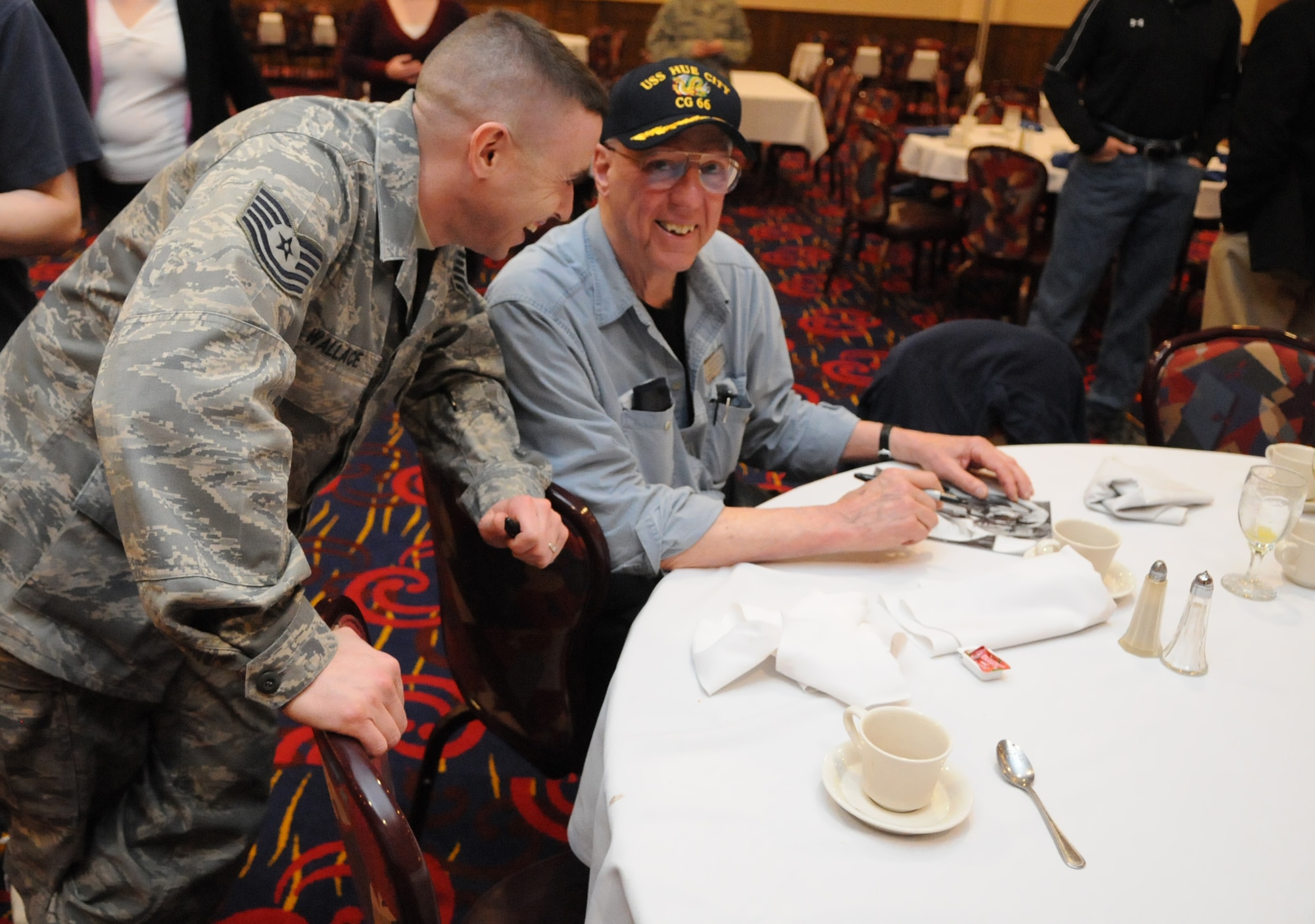 RAF MILDENHALL, England – David Hartman, former “Good Morning America” host, signs a photo and critiques a story Tech. Sgt. Kevin Wallace, 100th Air Refueling Wing Public Affairs, wrote about his participation in a March 11 “Legends of Aerospace: The Impossible Is Possible” tour the night prior at RAF Mildenhall’s Galaxy Club. Sergeant Wallace spent an hour talking to Mr. Hartman, Neil Armstrong and Gene Cernan in what he called an out-of-this-world breakfast.  (U.S. Air Force photo/Staff Sgt. Austin May)