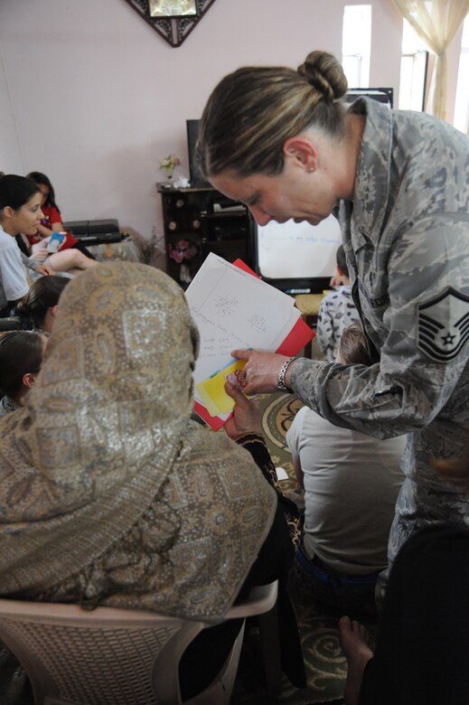 Air Force Master Sgt. Jessyca Hilar, a volunteer for the Iraqi women’s English speaking group, shows an Iraqi woman how to write a sentence about the picture on the card, Victory Base Complex, Iraq, March 9, 2010. The purpose of the informal women’s only group is to interact on a weekly basis and conduct English lessons for Iraqi women. (U.S. Air Force photo/Master Sgt. Trish Bunting/Released)