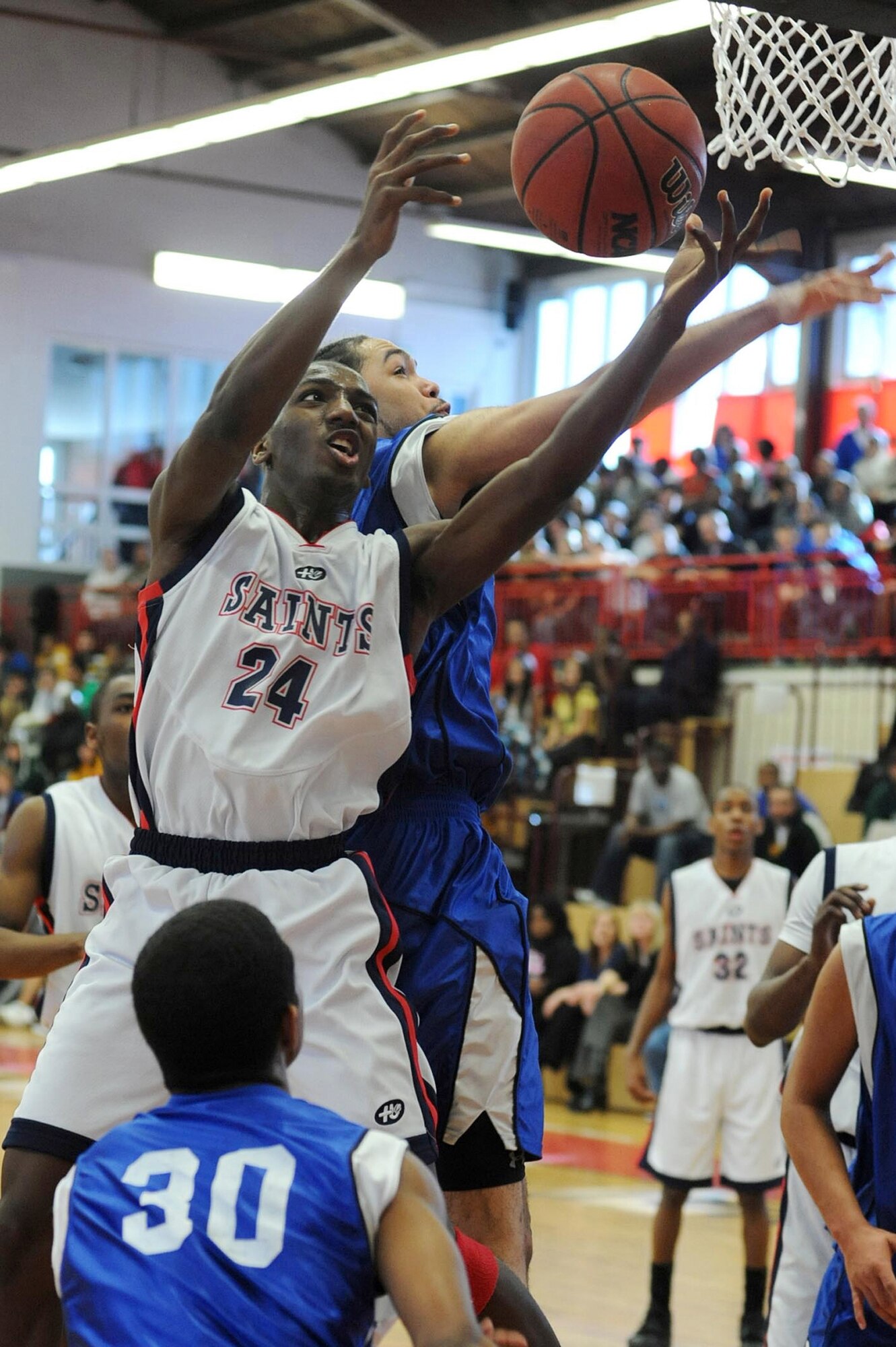 Aviano's Myron McRae, left, tries to put the ball in the basket in front of Jordan Gaddy of Hohenfels in the Division II final at the DODDS-Europe basketball championships in Mannheim, Germany, on Feb. 27th, 2010. Hohenfels' Jamie Thompkins watches for a rebound. Defending champion Aviano repeated with a 49-38 win.  (Photos by Michael Abrams.  Used with permission from the Stars and Stripes.  ? 2010 Stars and Stripes.)  
