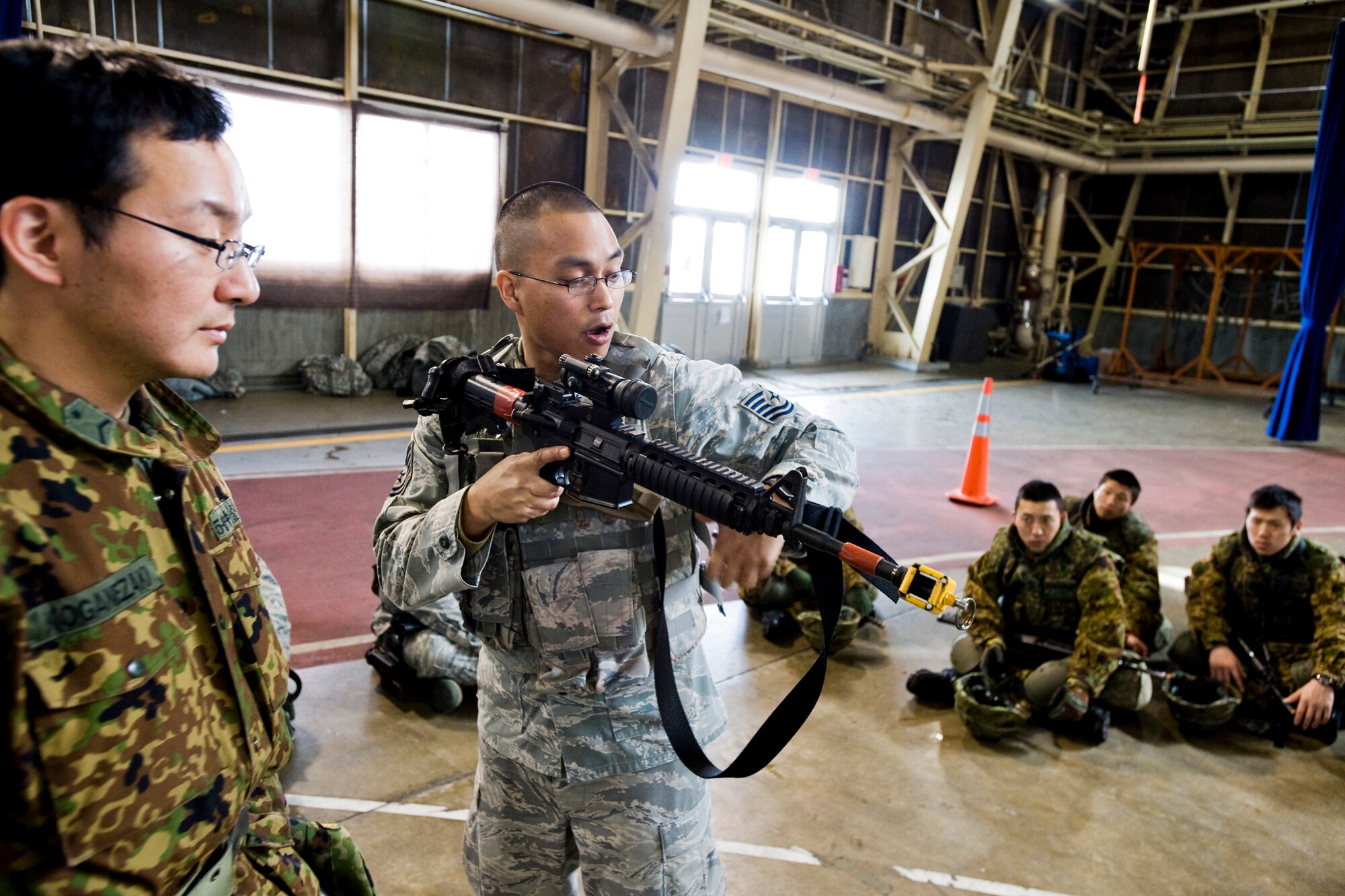 MISAWA AIR BASE, Japan -- Tech. Sgt. Ronnie Aldana, 35th Security Forces Squadron unit trainer, explains defensive tactics to Sergeant Takuro Koganezaki, Japan Ground Self-Defense Force 5th Infantry, 3rd Company, March 11 at Hangar 949. During the training, Sergeant Aldana covered defensive weapon and troop-movement tactics. (U.S. Air Force photo/Senior Airman Jamal D. Sutter)
