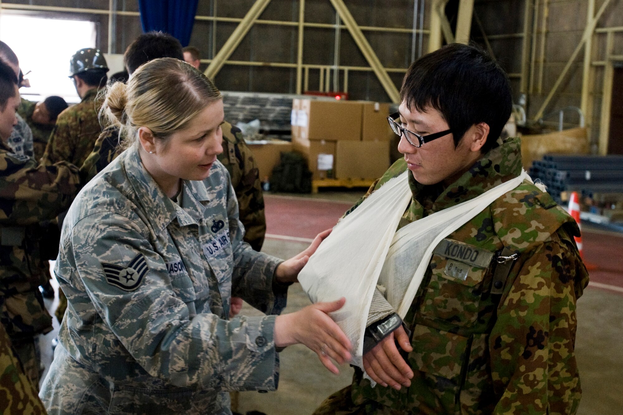 MISAWA AIR BASE, Japan -- Staff Sgt. Angeline Mason, 35th Security Forces Squadron unit education training manager, assists Leading Private Hiroki Kondo, Japan Ground Self-Defense Force 5th Infantry, 2nd Company, after applying a splint and sling to his arm March 11 at Hangar 949. In addition to self aid and buddy care, the training consisted of unexploded ordnance identification, troop-movement tactics and reporting procedures. (U.S. Air Force photo/Senior Airman Jamal D. Sutter)