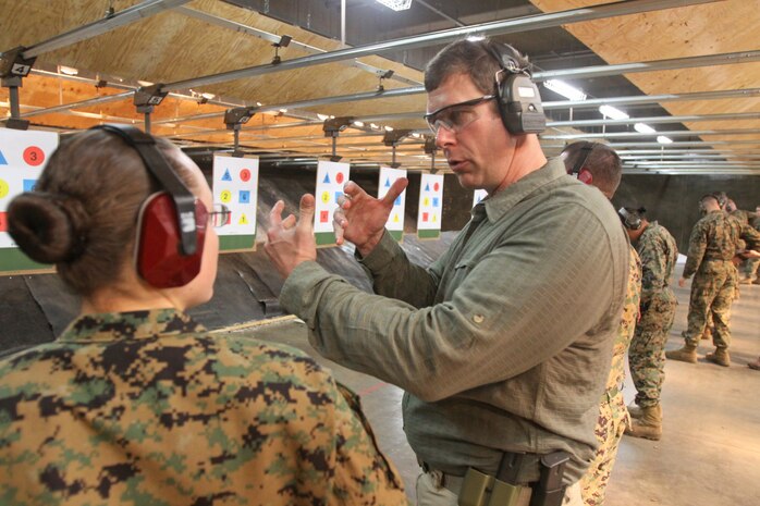 Jamison Elder, the founder and creator of Wolf-Tactical Reconnaissance and Personal Protection, better known as WOLF T.R.A.P.P., explains to a Marine the proper technique of drawing a pistol at the Indoor Small Arms Range here March 12.