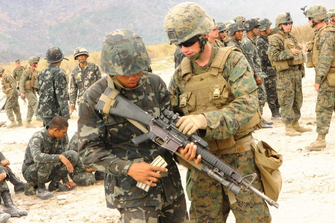 A Philippine Marine learns about the M16 A4 service rifle from a U.S. Marine with Battalion Landing Team 2nd Battalion, 7th Marines, 31st Marine Expeditionary Unit, looks on during a small-arms shoot at Crow Valley March 13, 2010. The small-arms shoot was part of bilateral training being conducted during Balikatan 2010. The exercise is a Government of the Republic of the Philippines-approved and U.S. Joint Chiefs of Staff-directed annual bilateral exercise with AFP personnel, select experts from Philippine civil defense agencies and U.S. military.