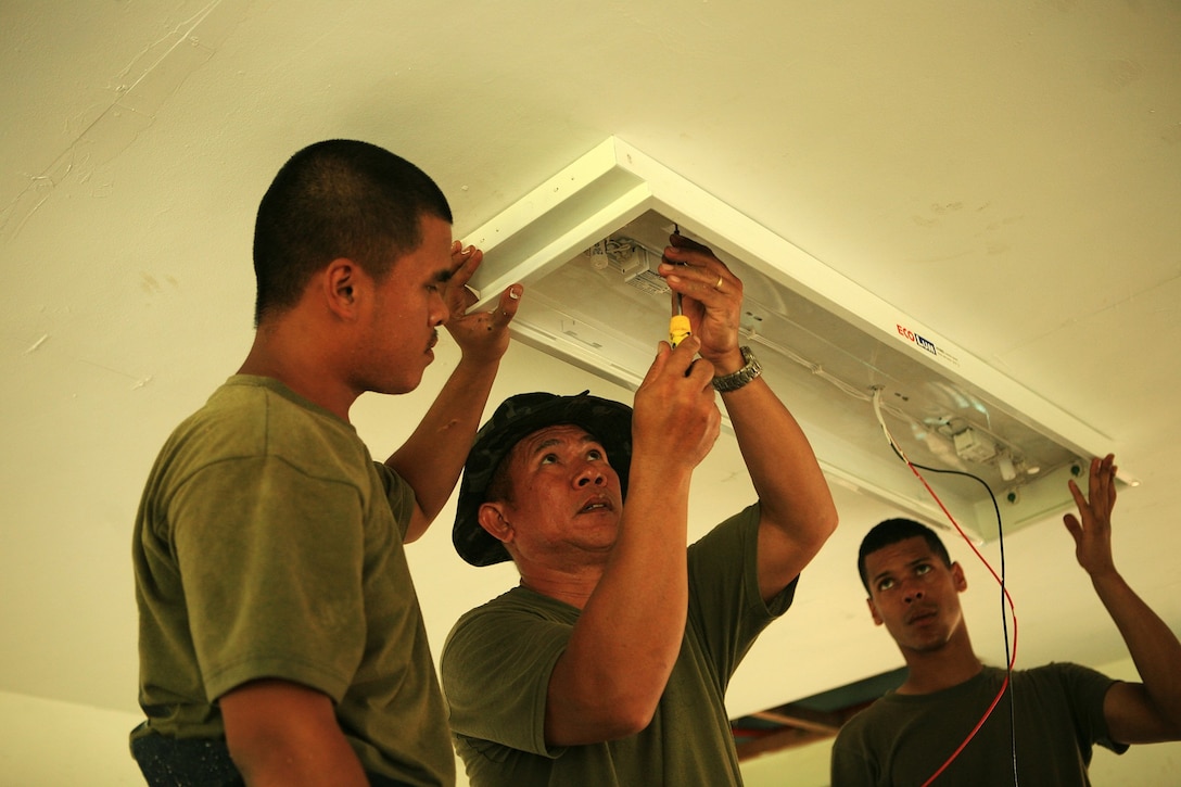 Lance corporals Orland Macaspac (left) and Anthony Baez (right), both electricians with Combat Logistics Battalion 31 (CLB-31), 31st Marine Expeditionary Unit (MEU), and Tech. Sgt. Antipatro Hilvano (center), an electrician with Engineering Landing Support Company, Service Support Battalion, Philippine Marine Corps, install a fluorescent light fixture in a two-room classroom during an engineering civil affairs project (ENCAP) at Marnay Primary School, March 13. CLB-31 along with the Armed Forces of the Philippines (AFP) are renovating the school to support the local Filipino community in support of exercise Balikatan 2010 (BK ’10). (Official Marine Corps photo by Lance Cpl. Dengrier M. Baez)